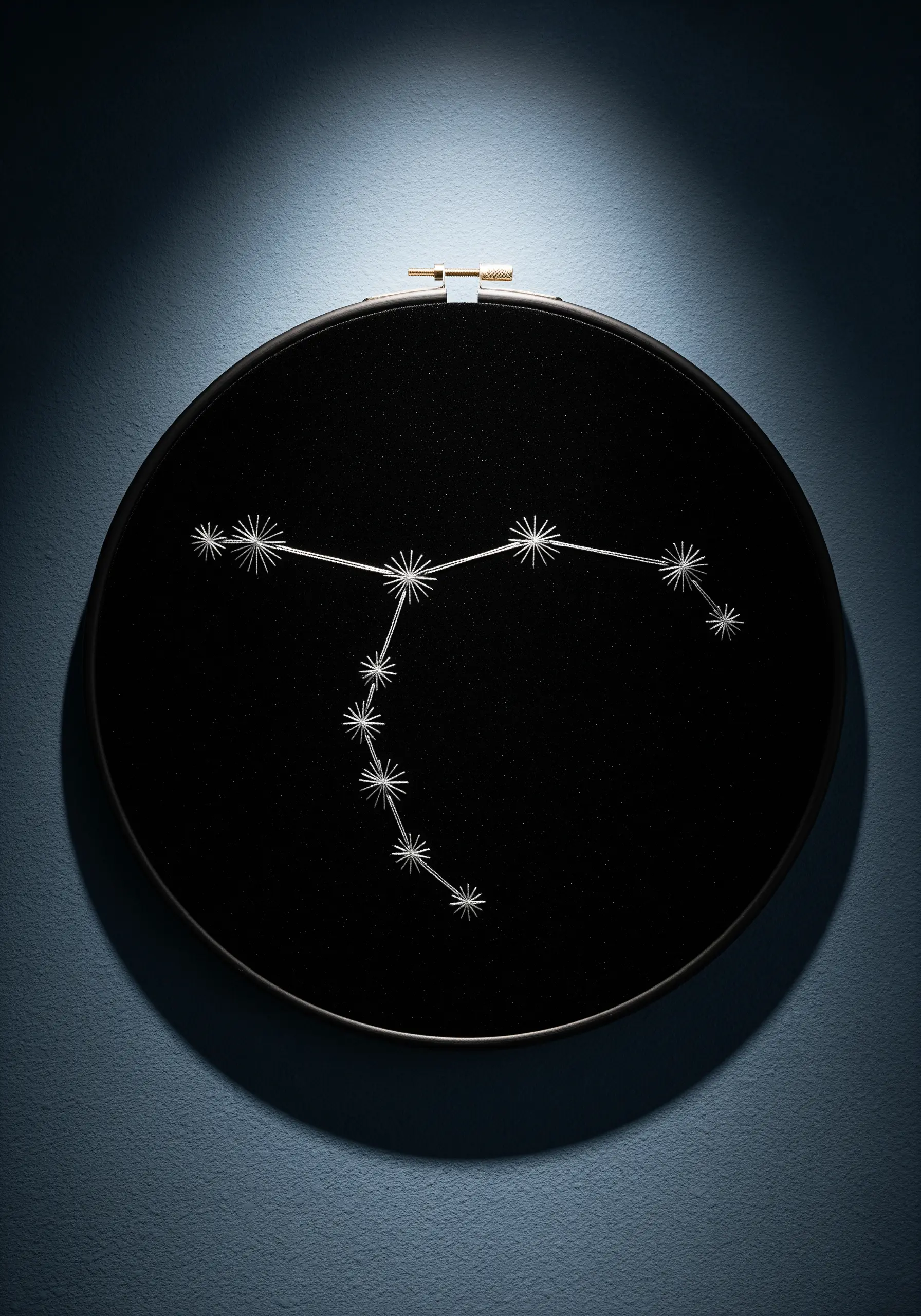 An embroidered constellation with starburst stitches in white thread on black fabric in a hoop.