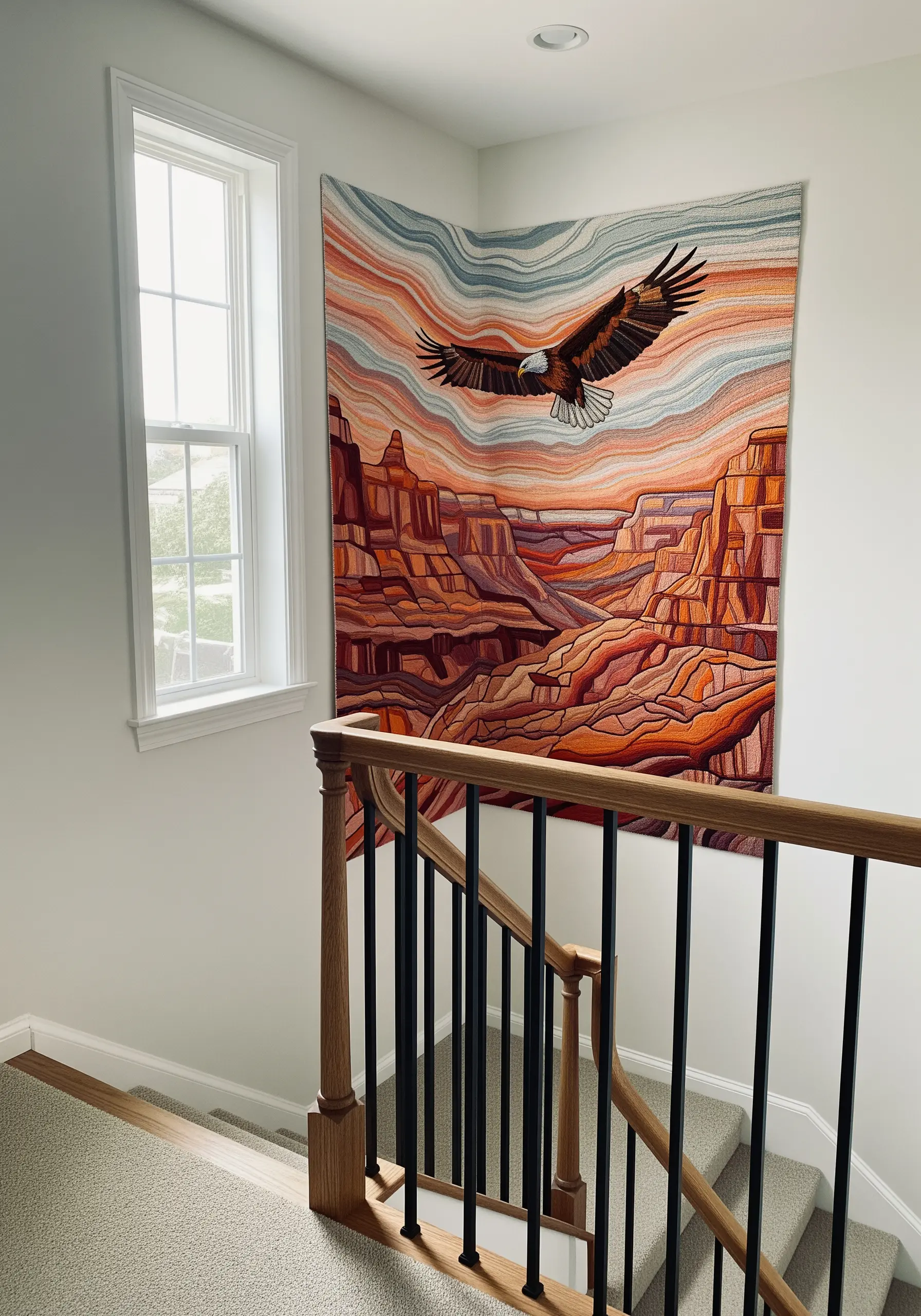 A large embroidered tapestry of an eagle soaring over a canyon, hung on a staircase wall.