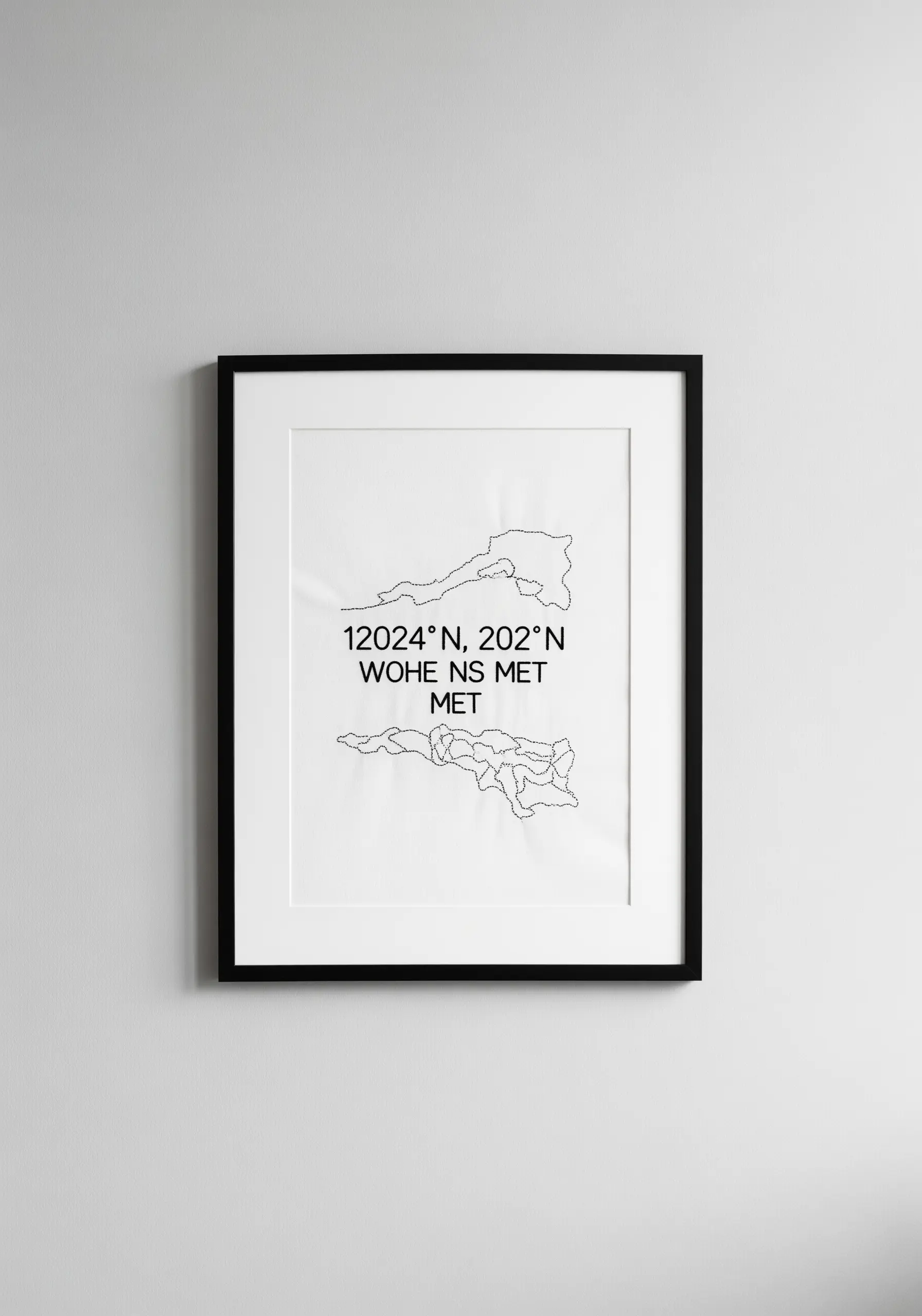Framed minimalist embroidery of two land masses and coordinates in black thread on white.