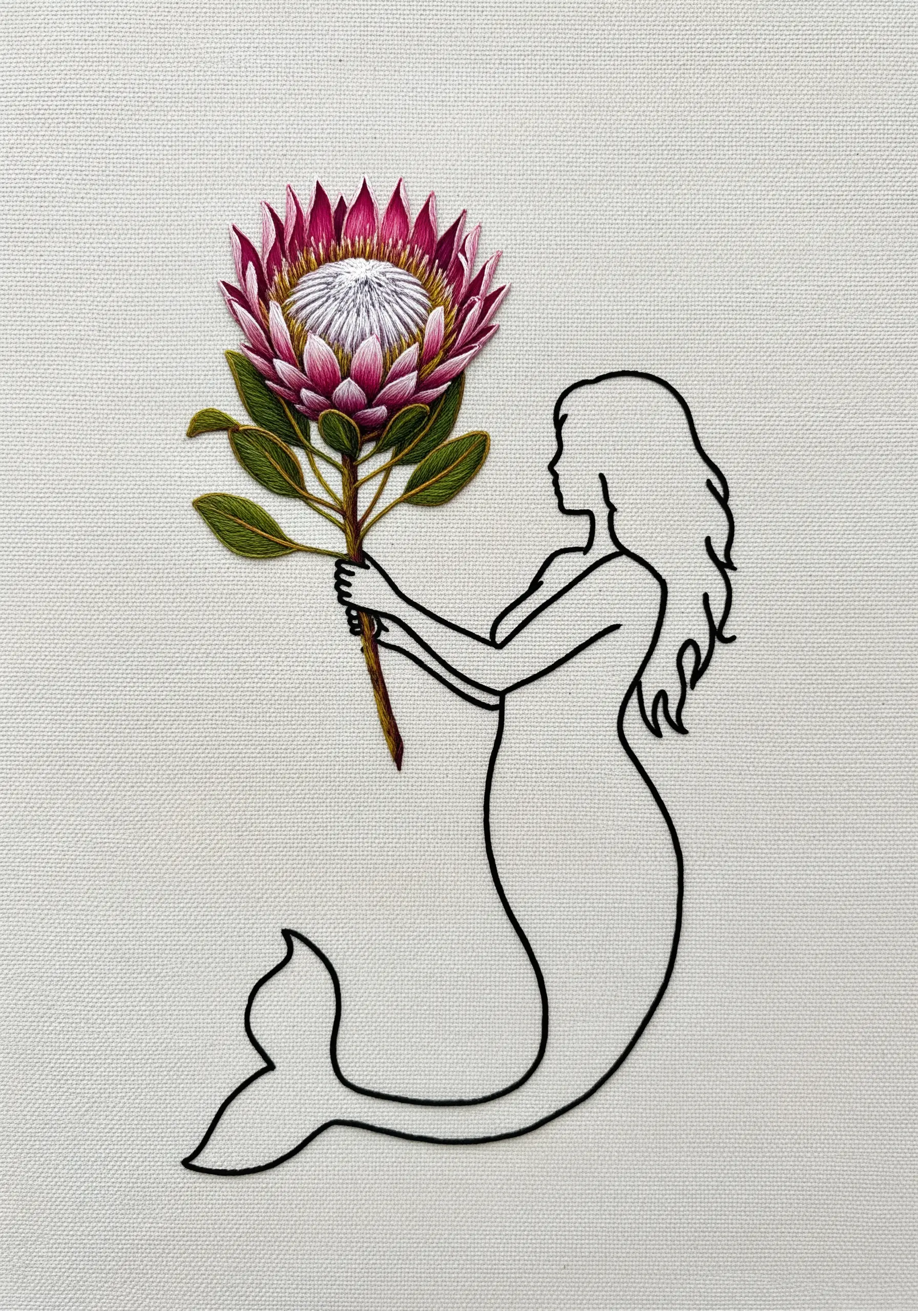 A minimalist black line art embroidery of a mermaid holding a large, fully thread-painted protea flower.