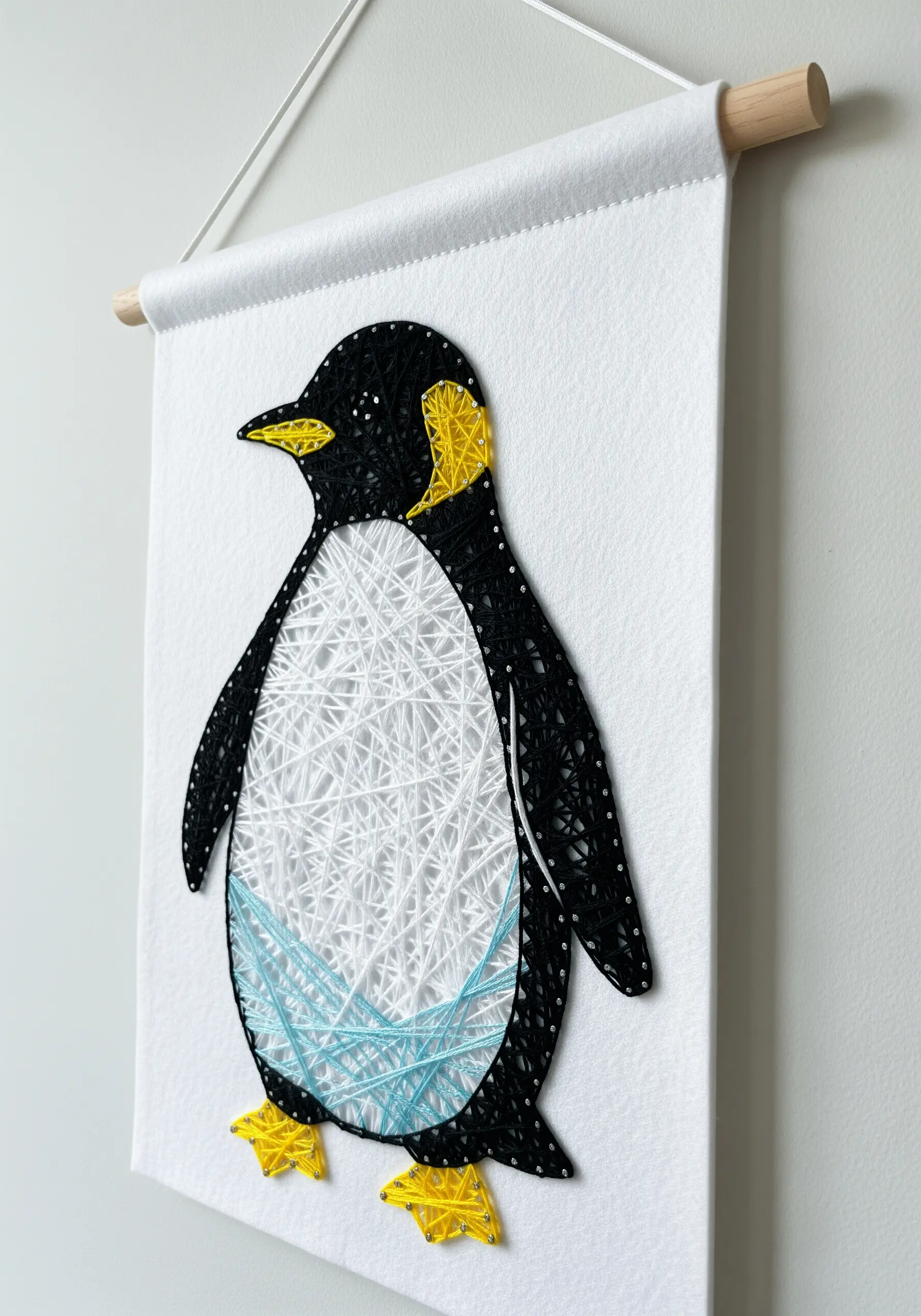 Penguin embroidery on a white felt banner with clean black, white, and yellow sections.