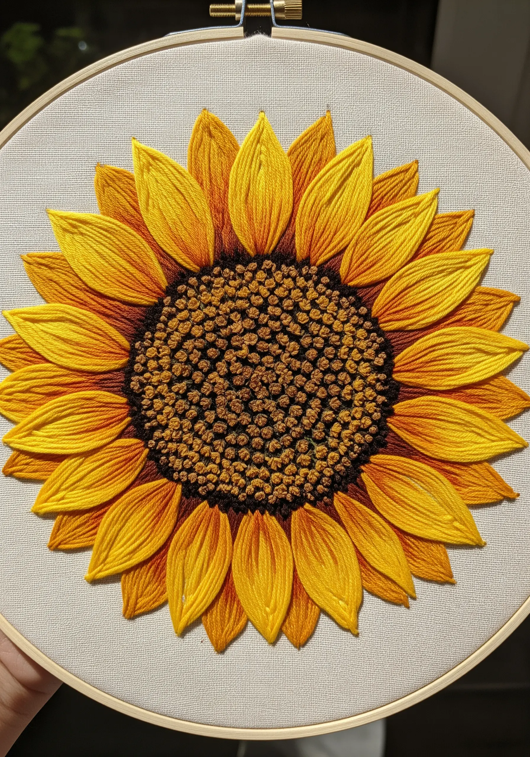 A detailed embroidered sunflower with a French knot center and satin stitch petals.