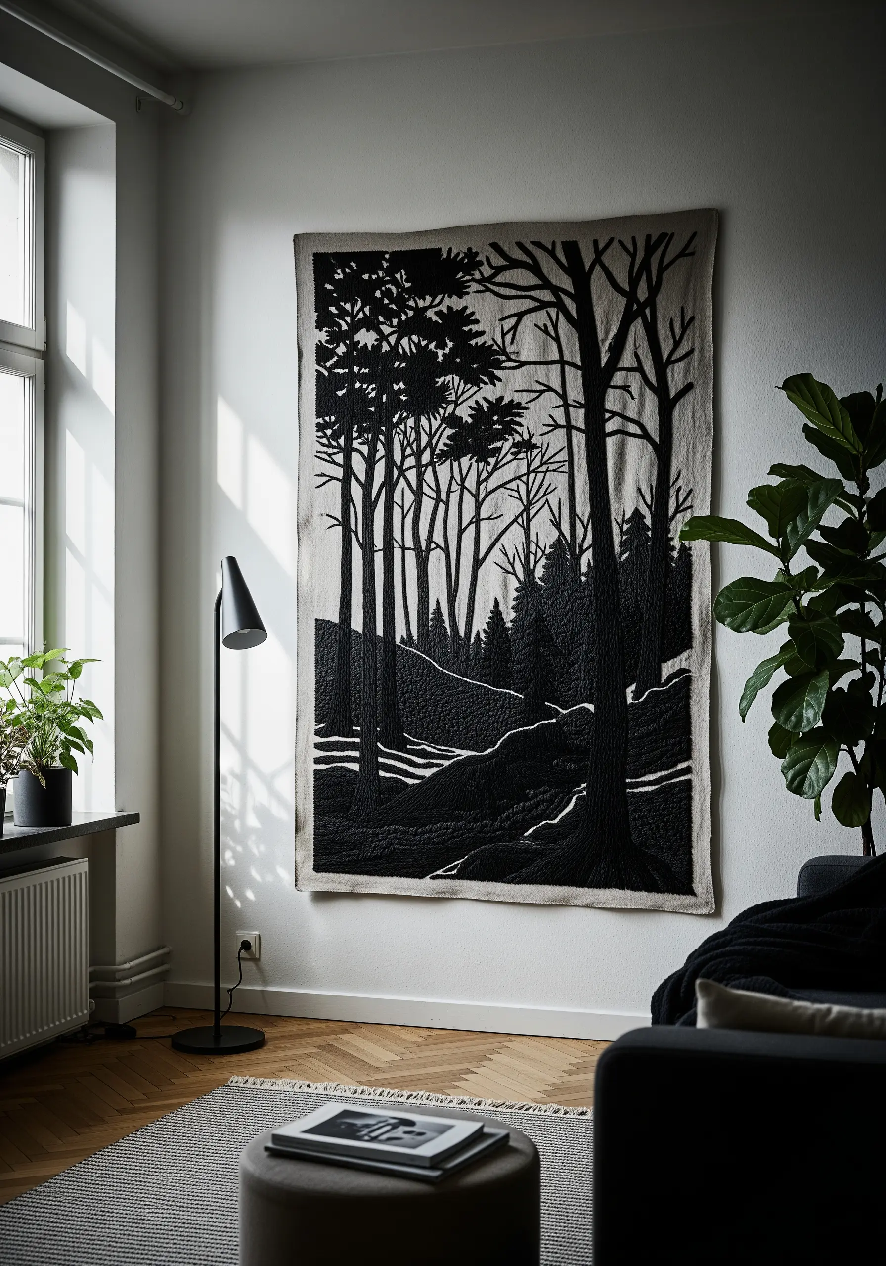 Large-scale black thread embroidery of a forest scene hanging on a white wall.