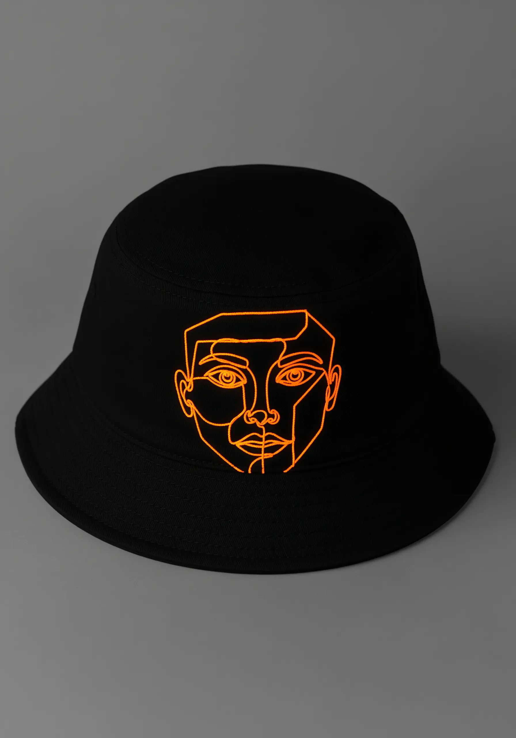 A minimalist one-line portrait embroidered in neon orange on a black bucket hat.