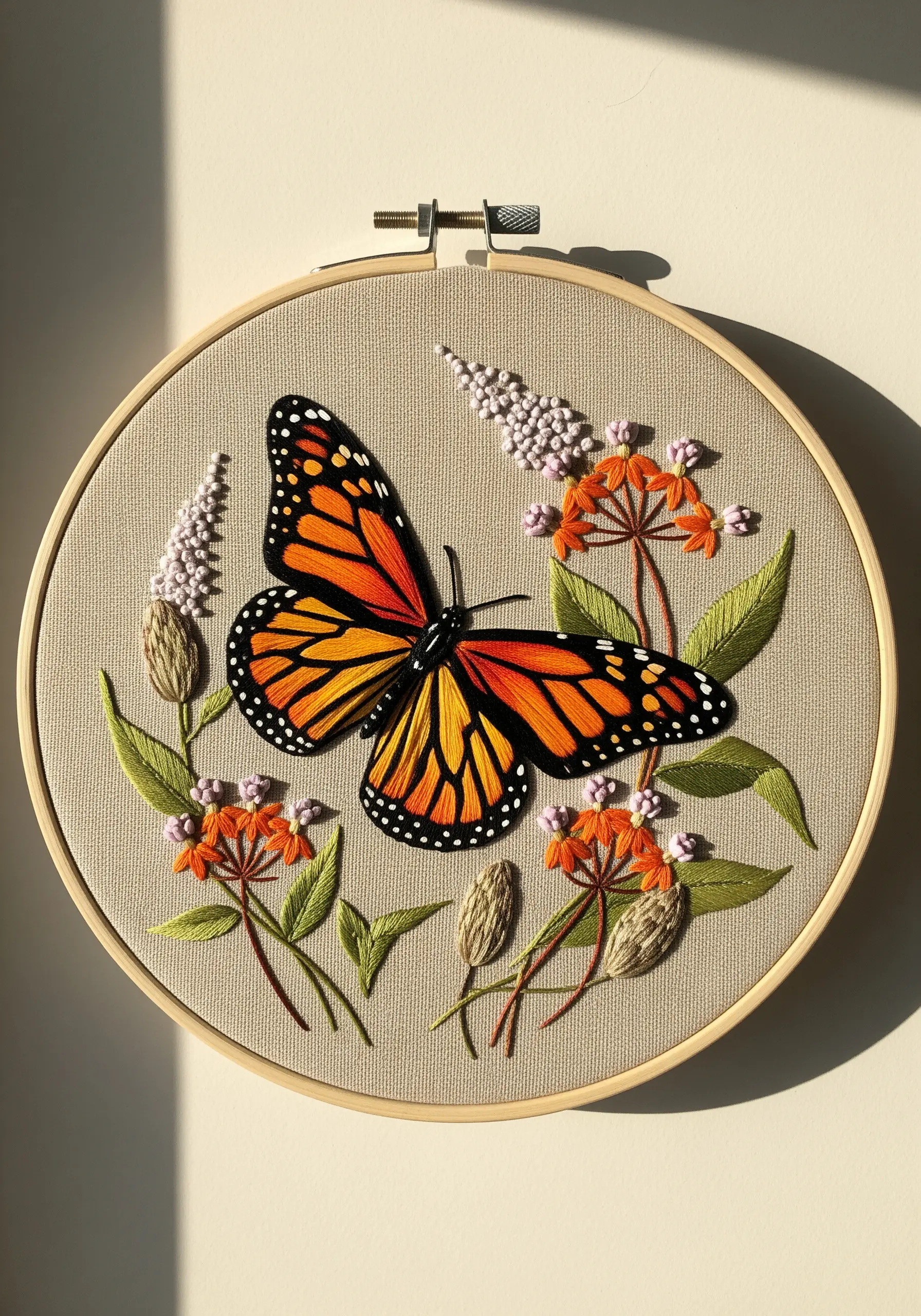 Embroidered Monarch butterfly with detailed thread painting on beige fabric.