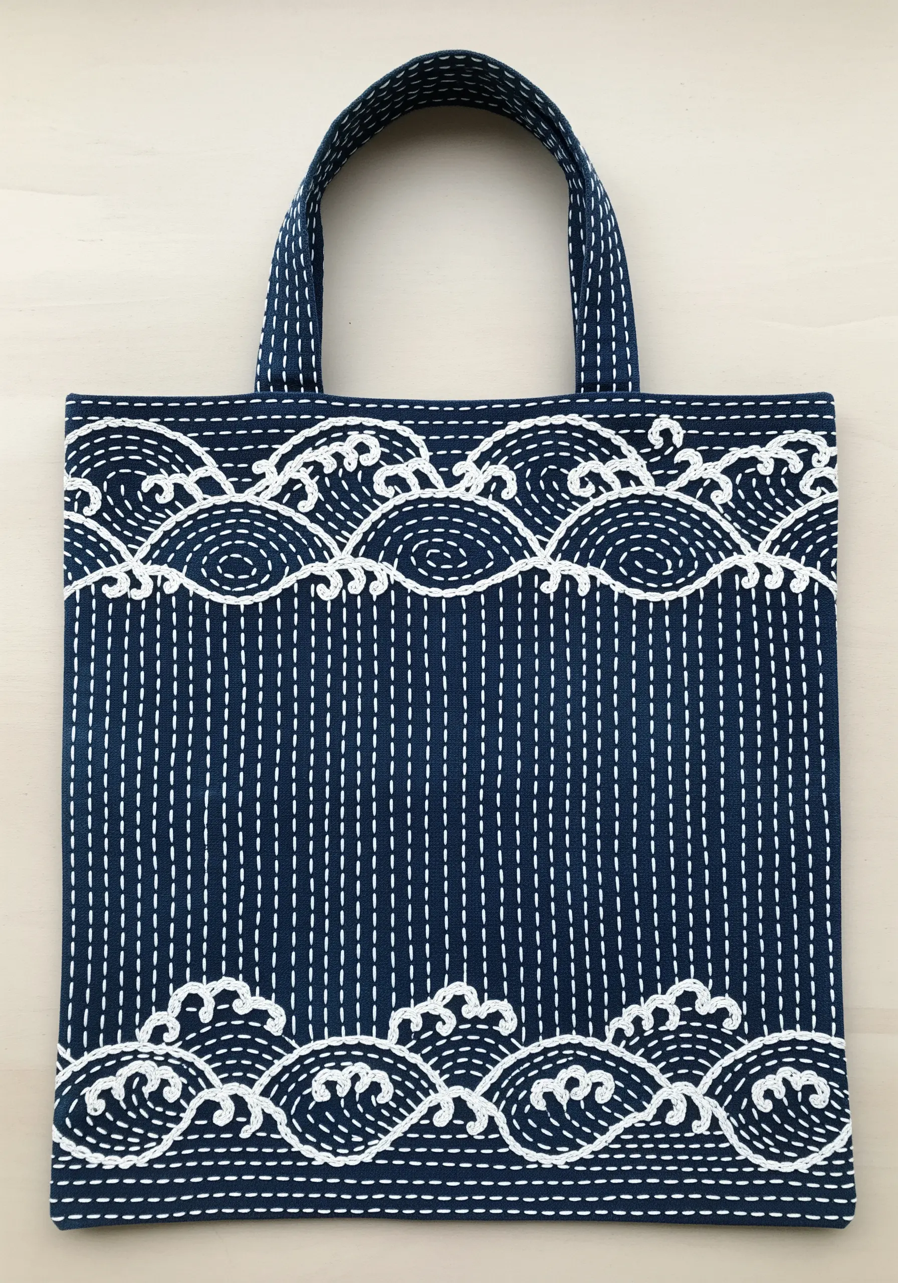 Japanese Sashiko embroidery featuring a wave pattern in white thread on an indigo blue tote bag.
