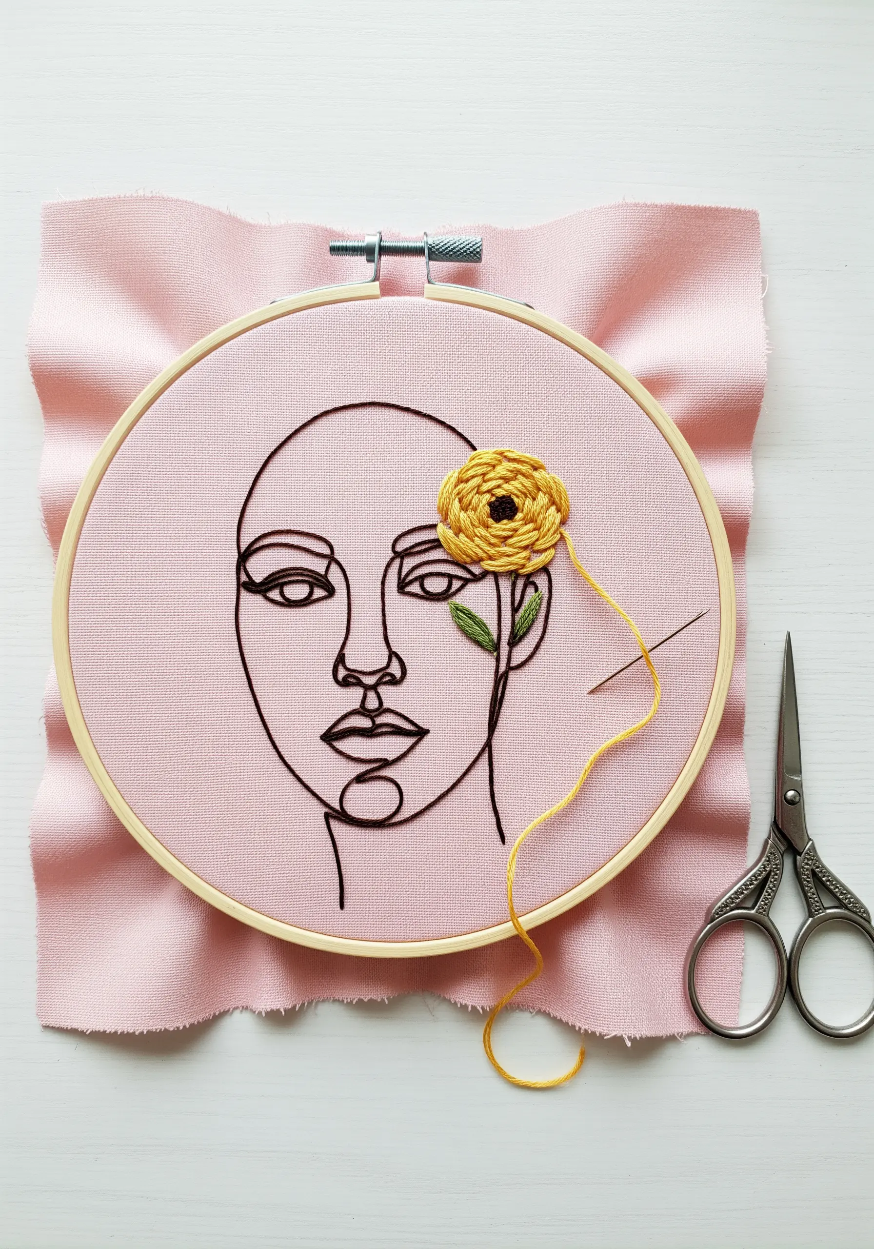 Line-art portrait with a yellow 3D woven wheel flower stitched over one eye.