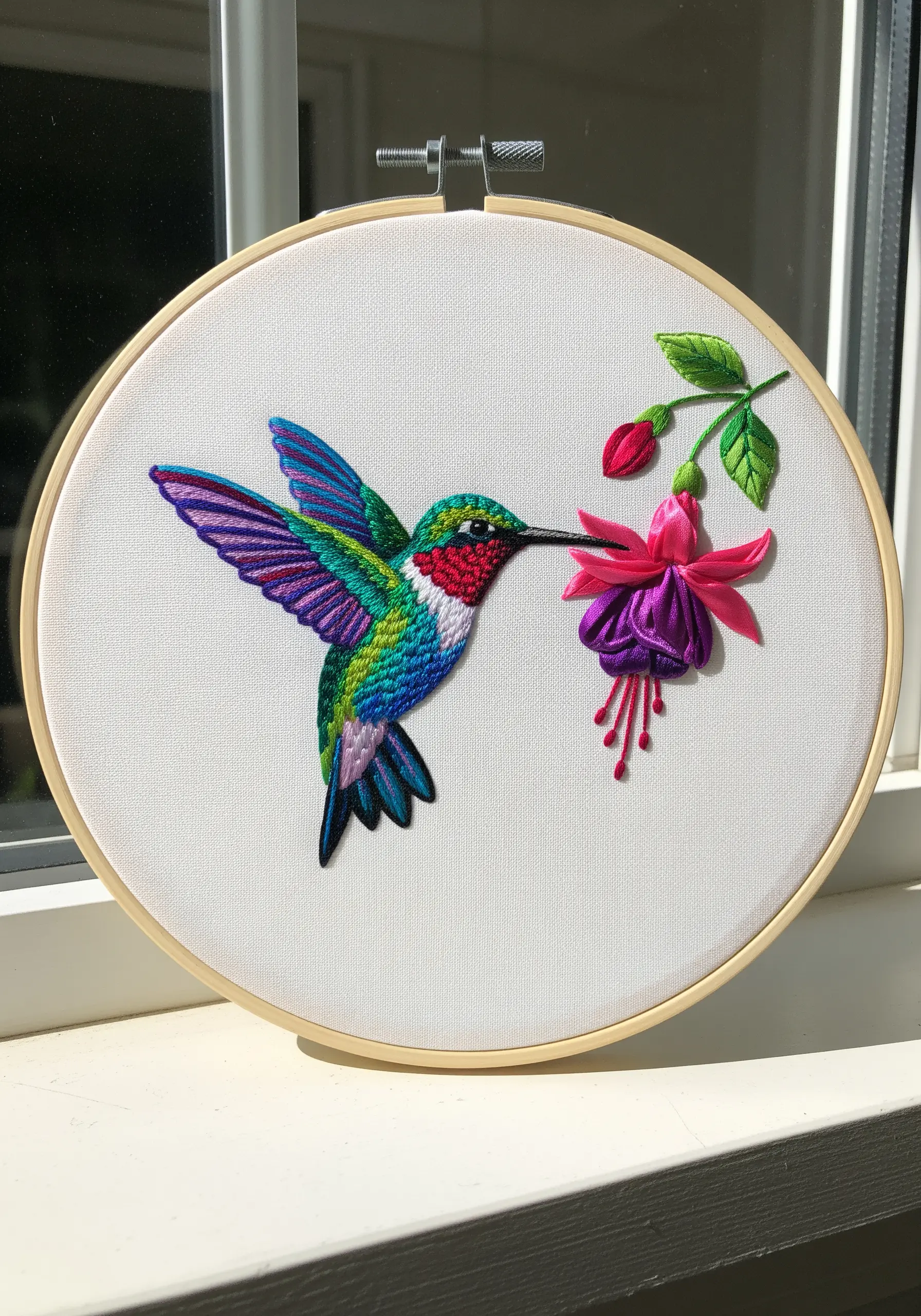Vibrant hummingbird embroidery with satin-stitched color blocks and a 3D fuchsia flower.