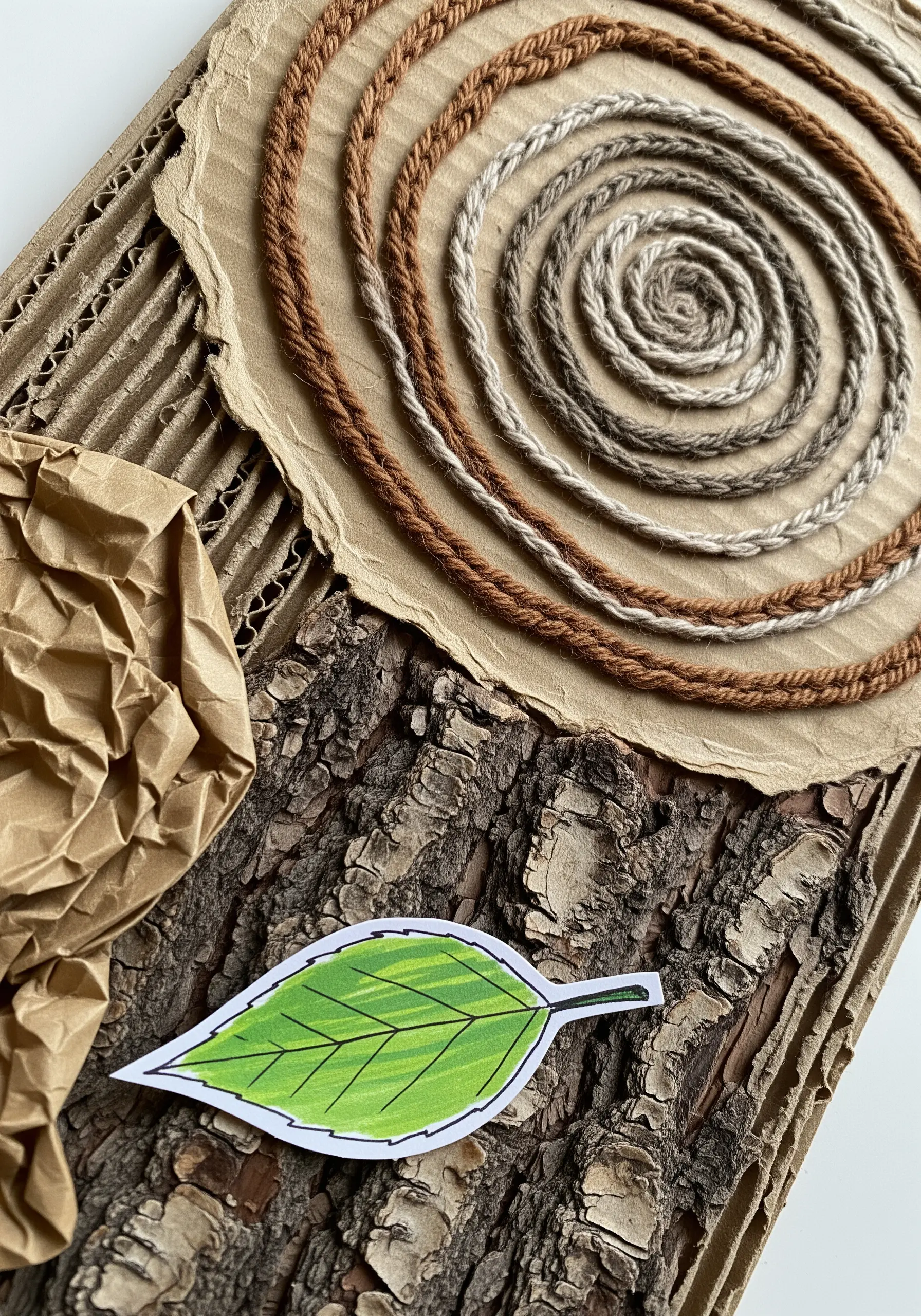 A nature-themed collage with coiled yarn spirals next to real tree bark and corrugated cardboard.