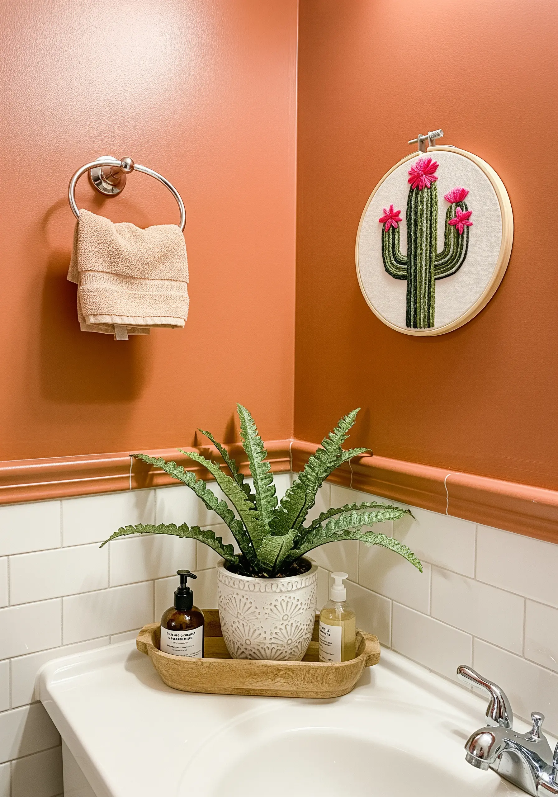 An embroidered cactus with vertical satin stitches and bright pink flowers.