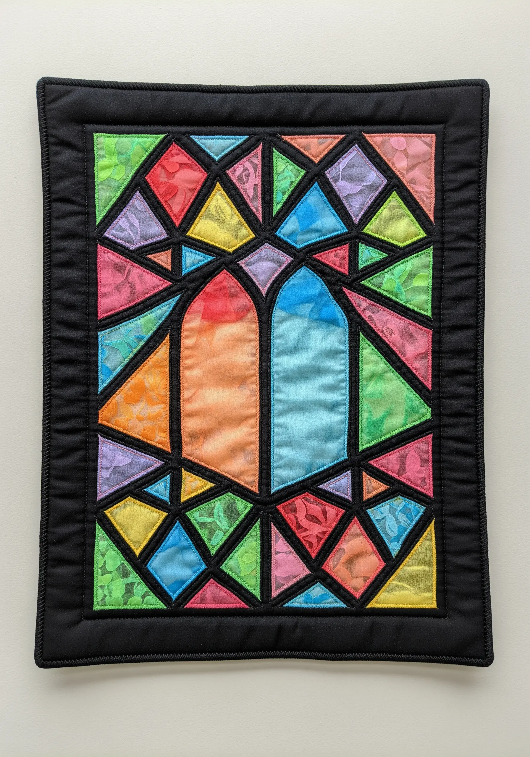 A stained-glass window effect created with colorful sheer fabrics and bold black outlines.