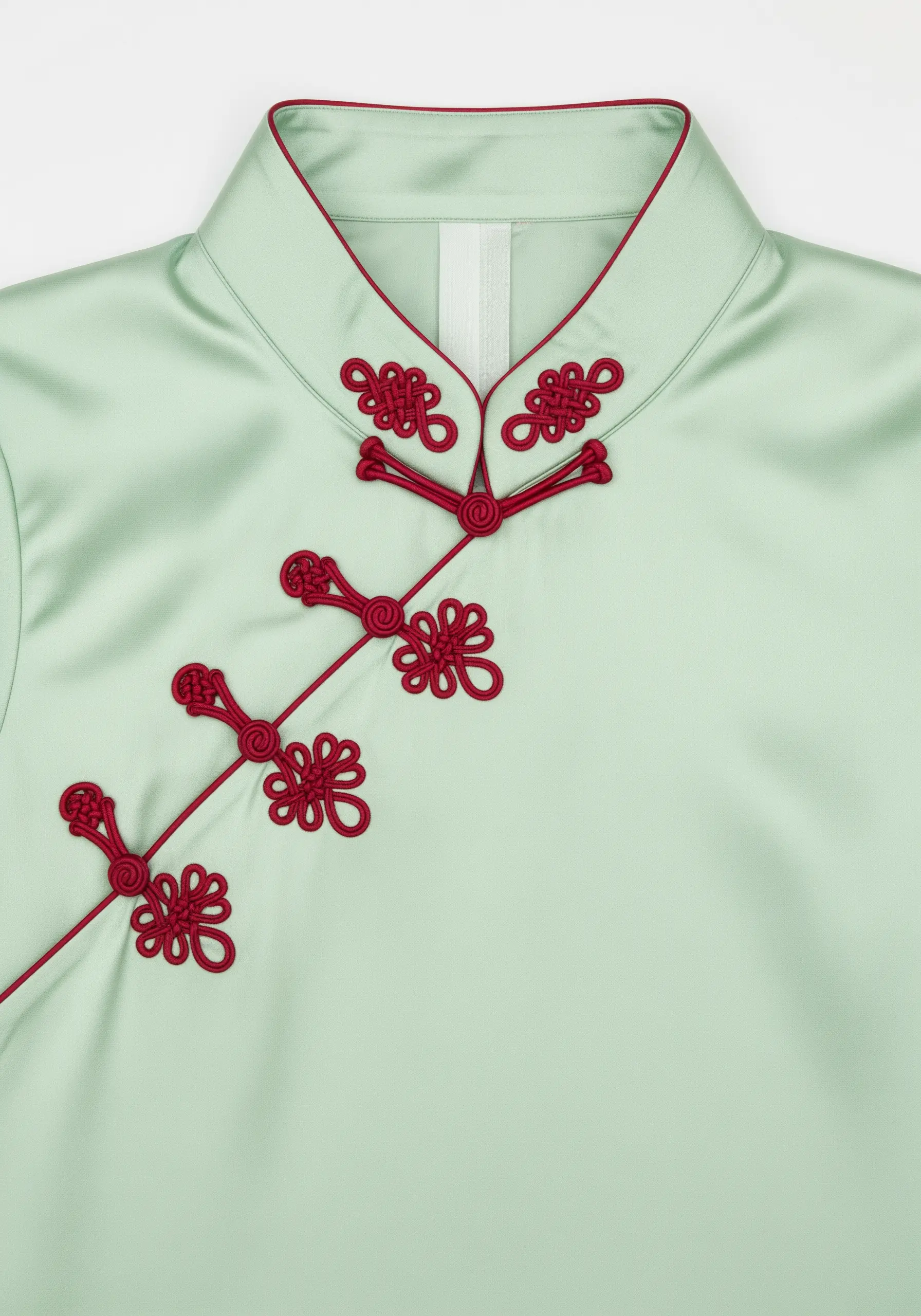 Red decorative frog closures in an intricate knot pattern on a mint green silk blouse.