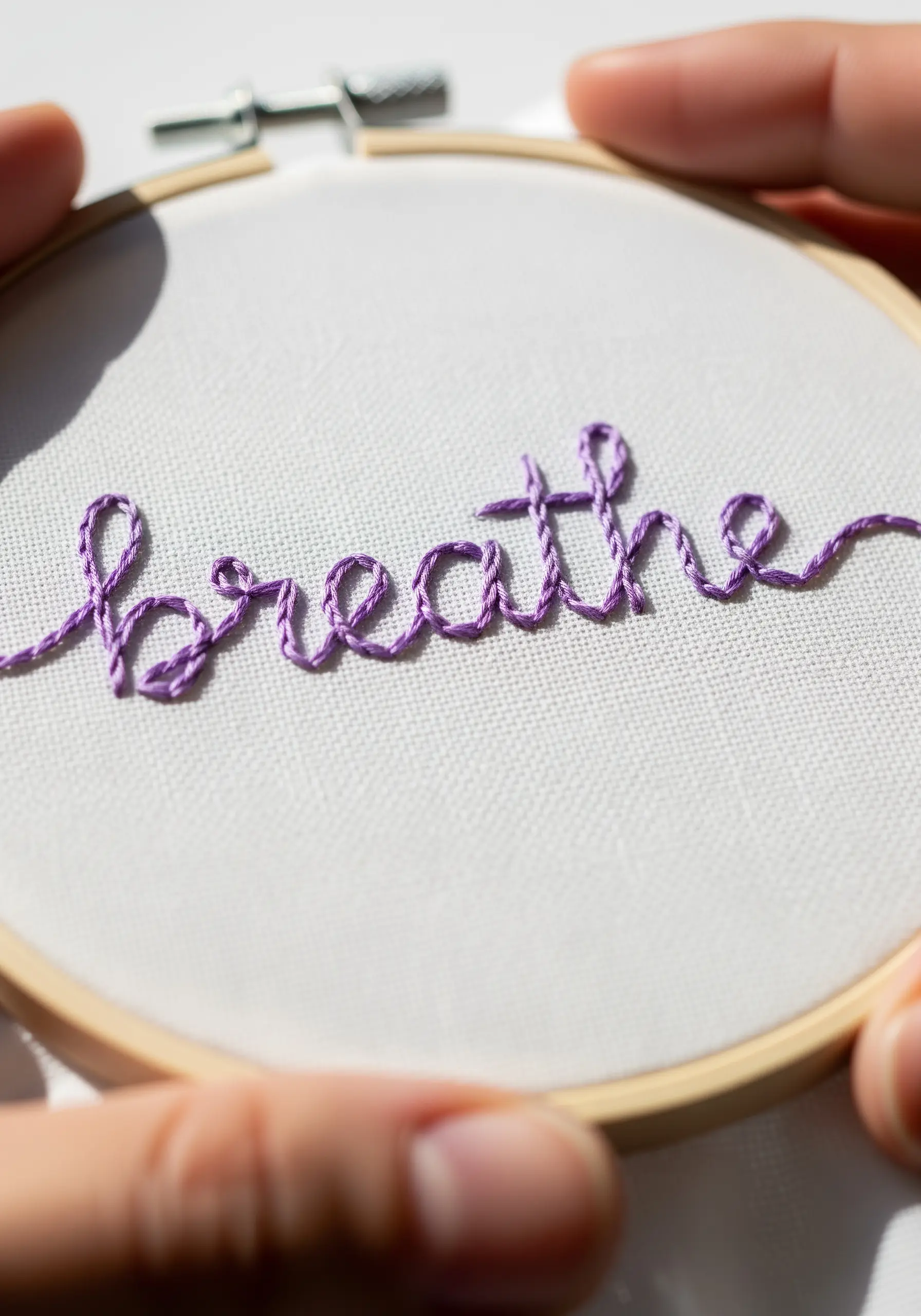 The word 'breathe' stitched in purple whipped backstitch for a raised, cursive effect.