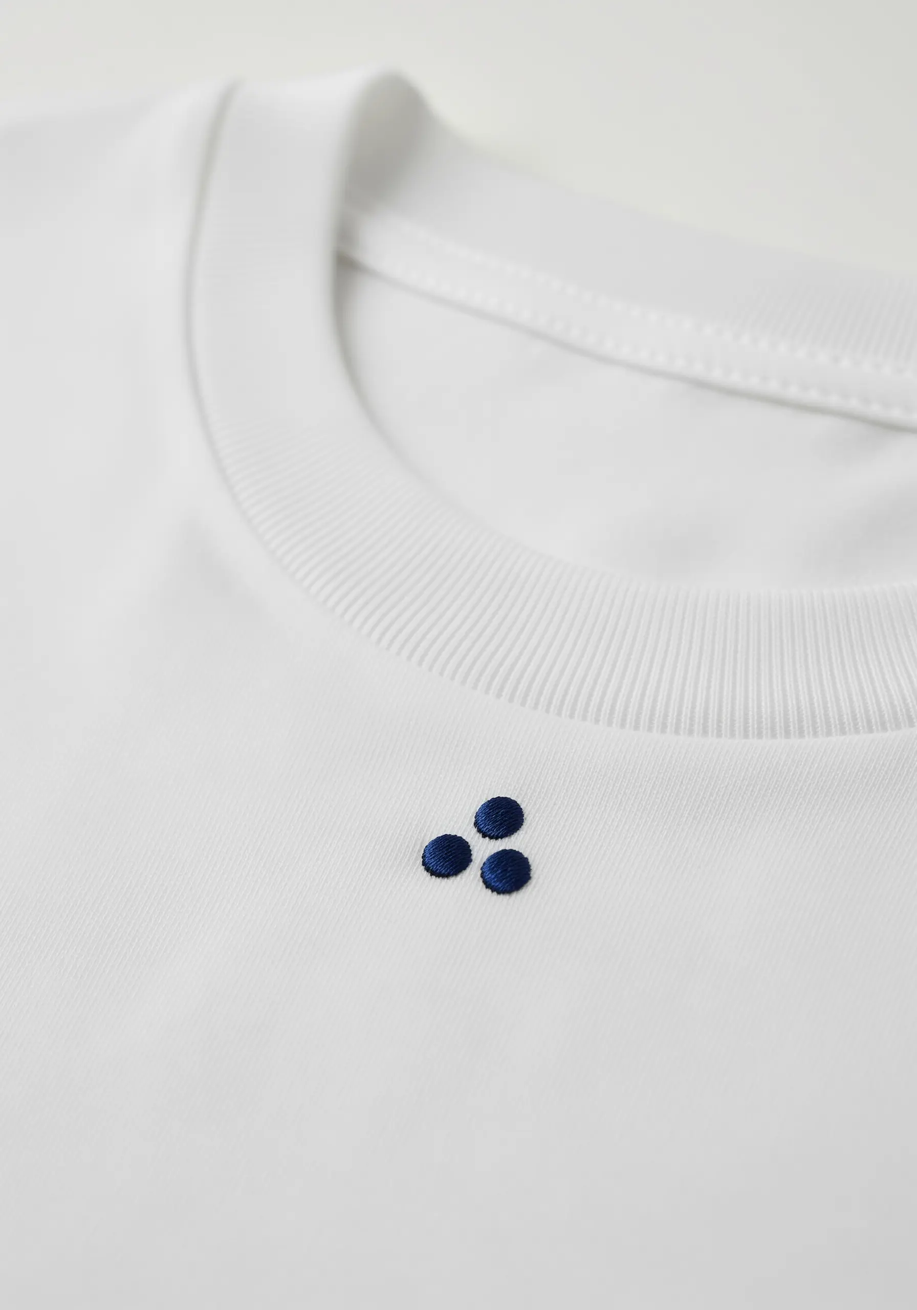 Three small, perfectly round navy blue dots embroidered near the collar.