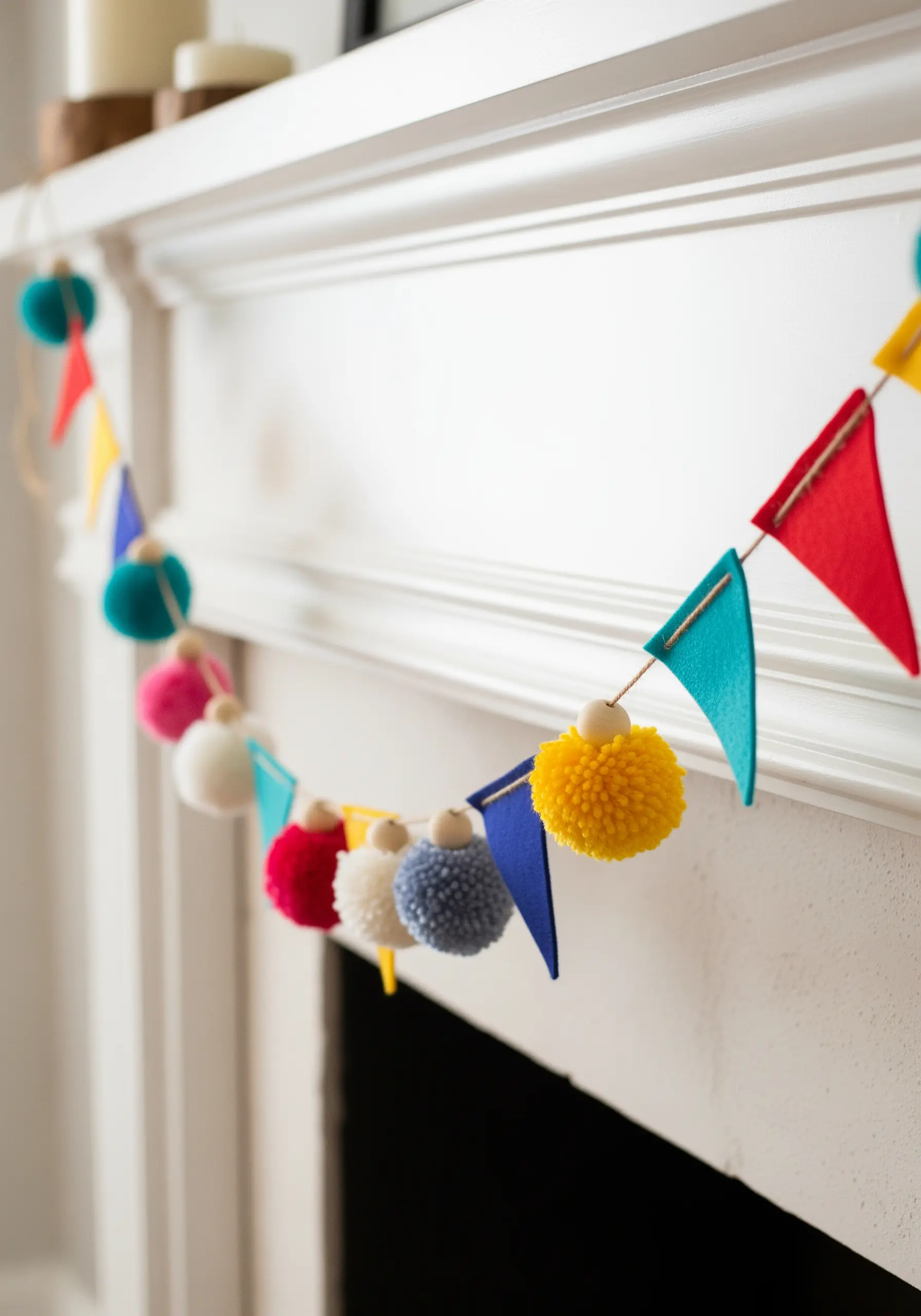 A colorful garland made of felt flags and yarn pom-poms on a white mantelpiece.