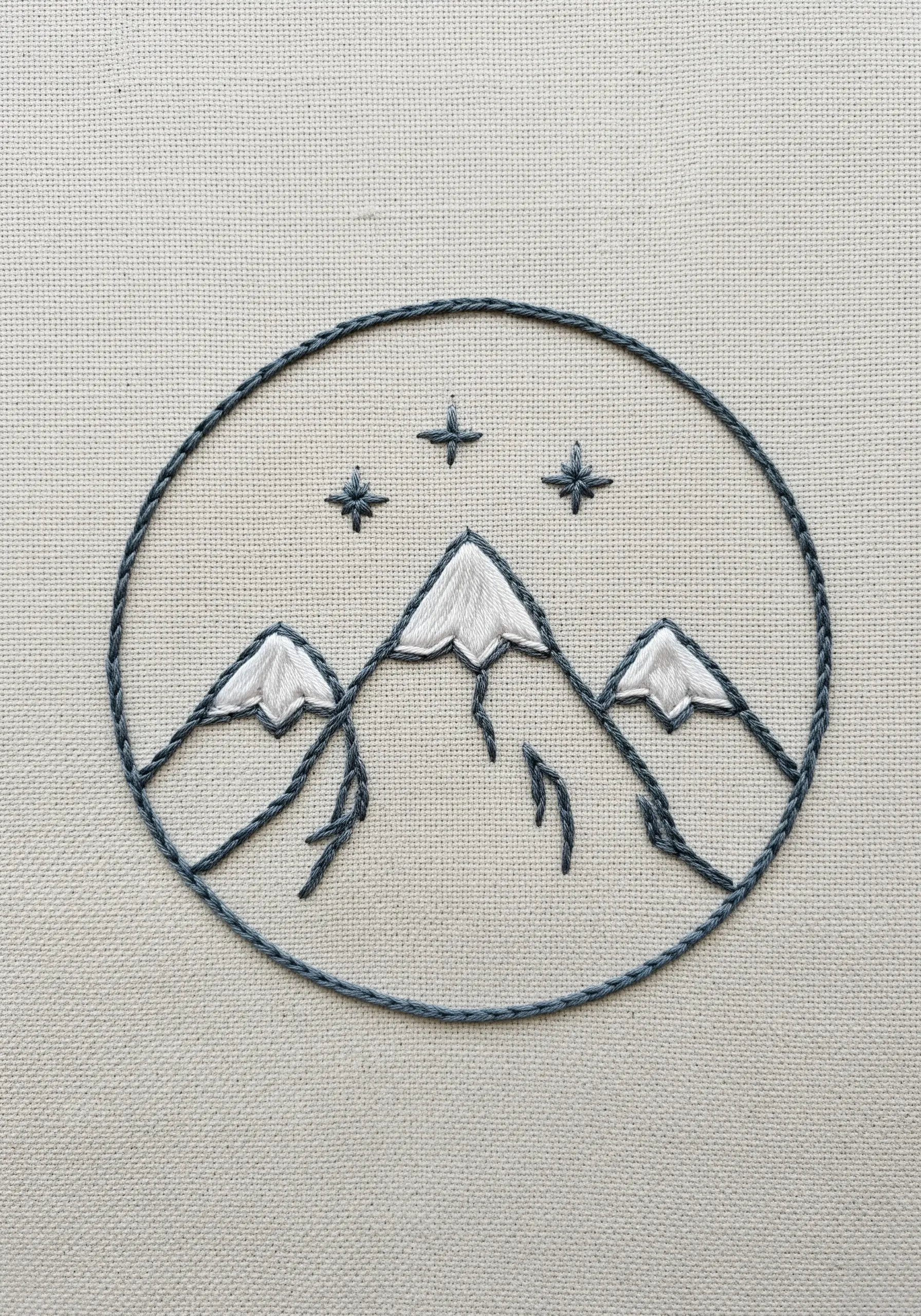 Minimalist mountain line art embroidery inside a circular border