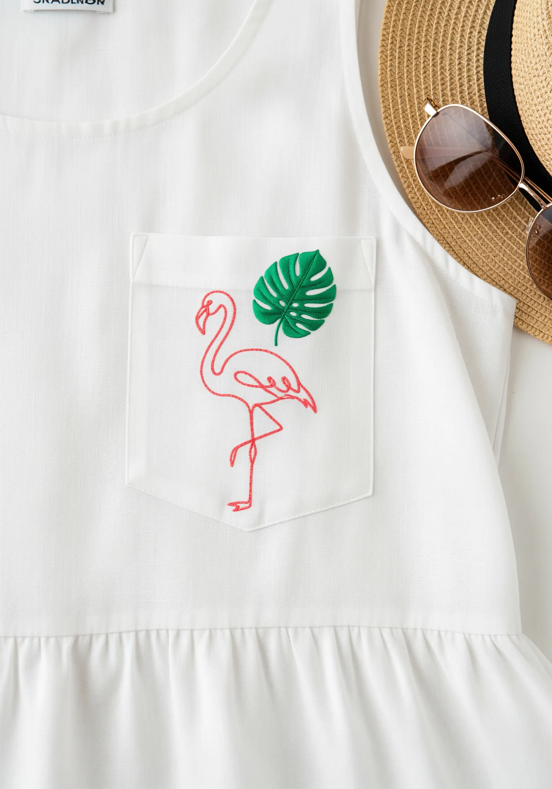 Minimalist red line art flamingo with a green satin-stitched leaf on a white dress pocket.