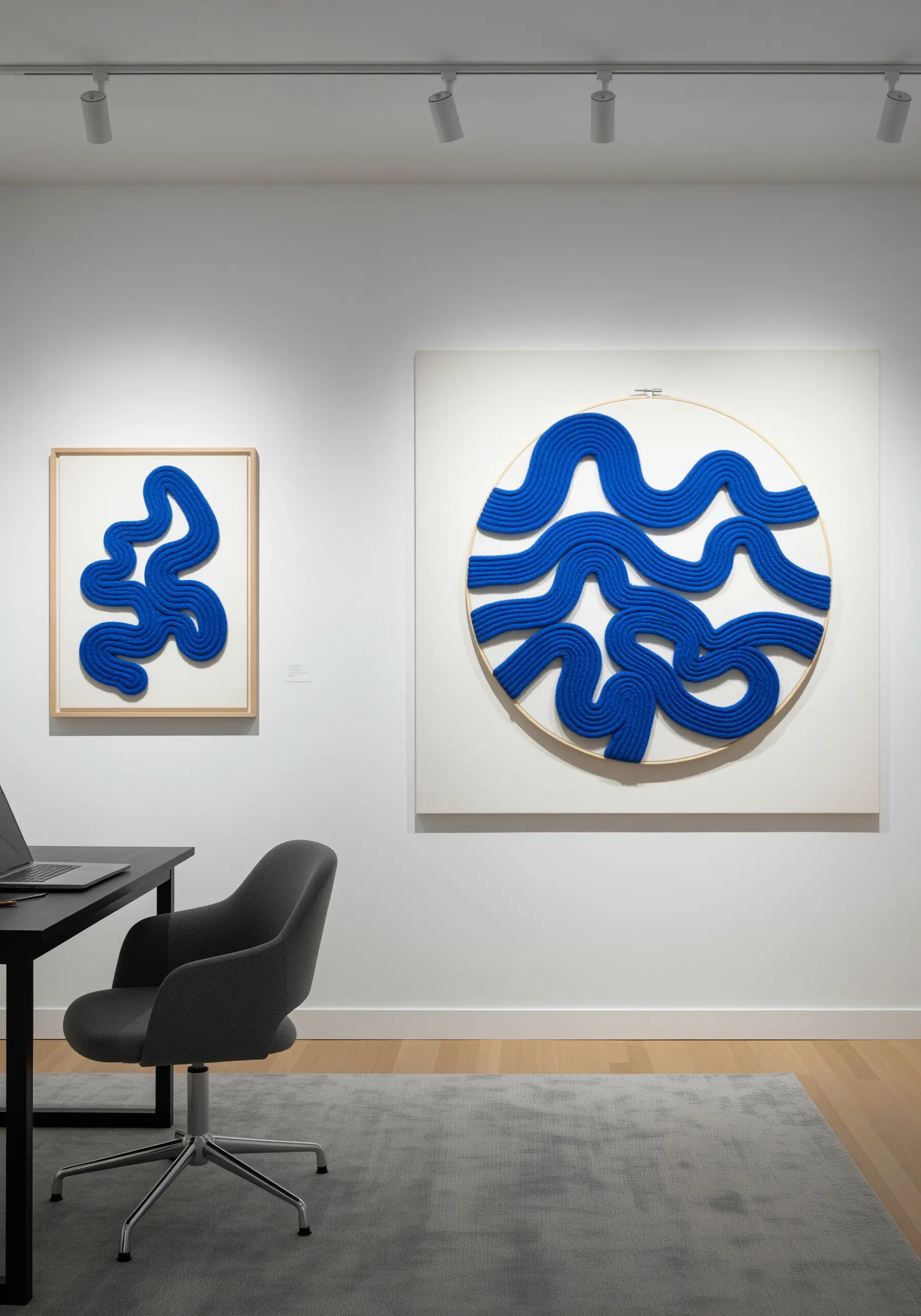 Modern art display with minimalist blue yarn couched in a wave pattern on white canvas.
