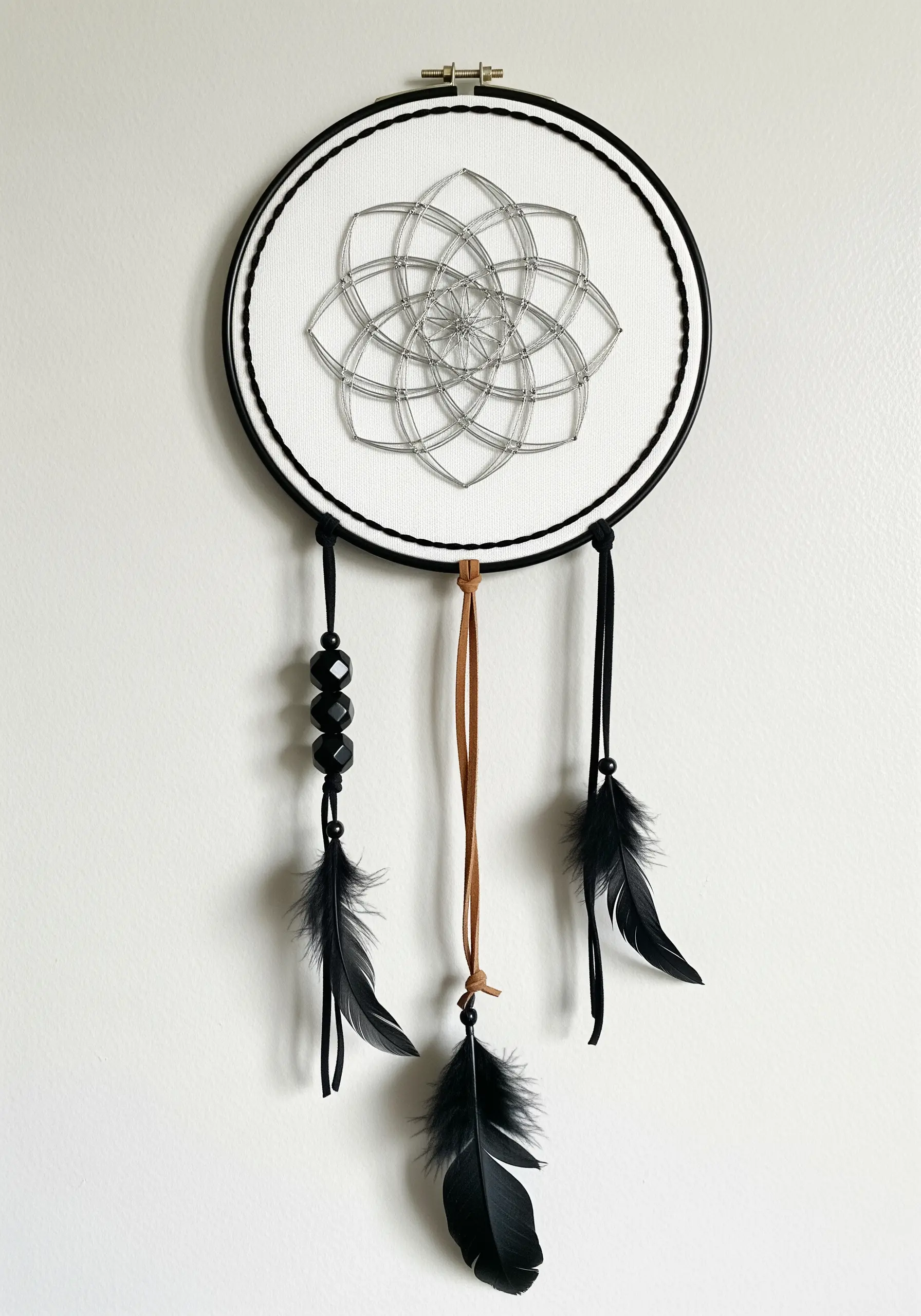 Minimalist silver string art in a geometric flower pattern on a white background.