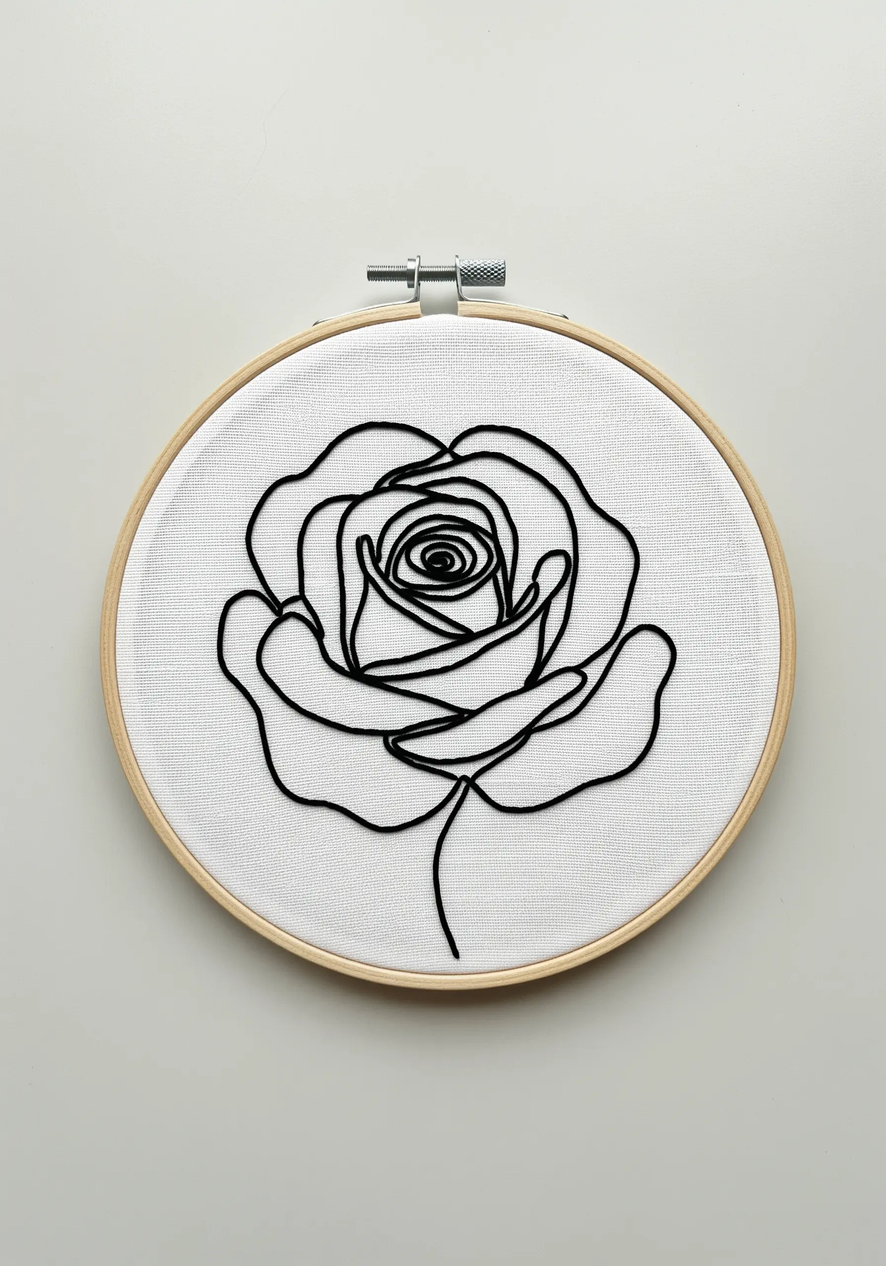 A single continuous black line forming a rose outline, embroidered on white fabric.