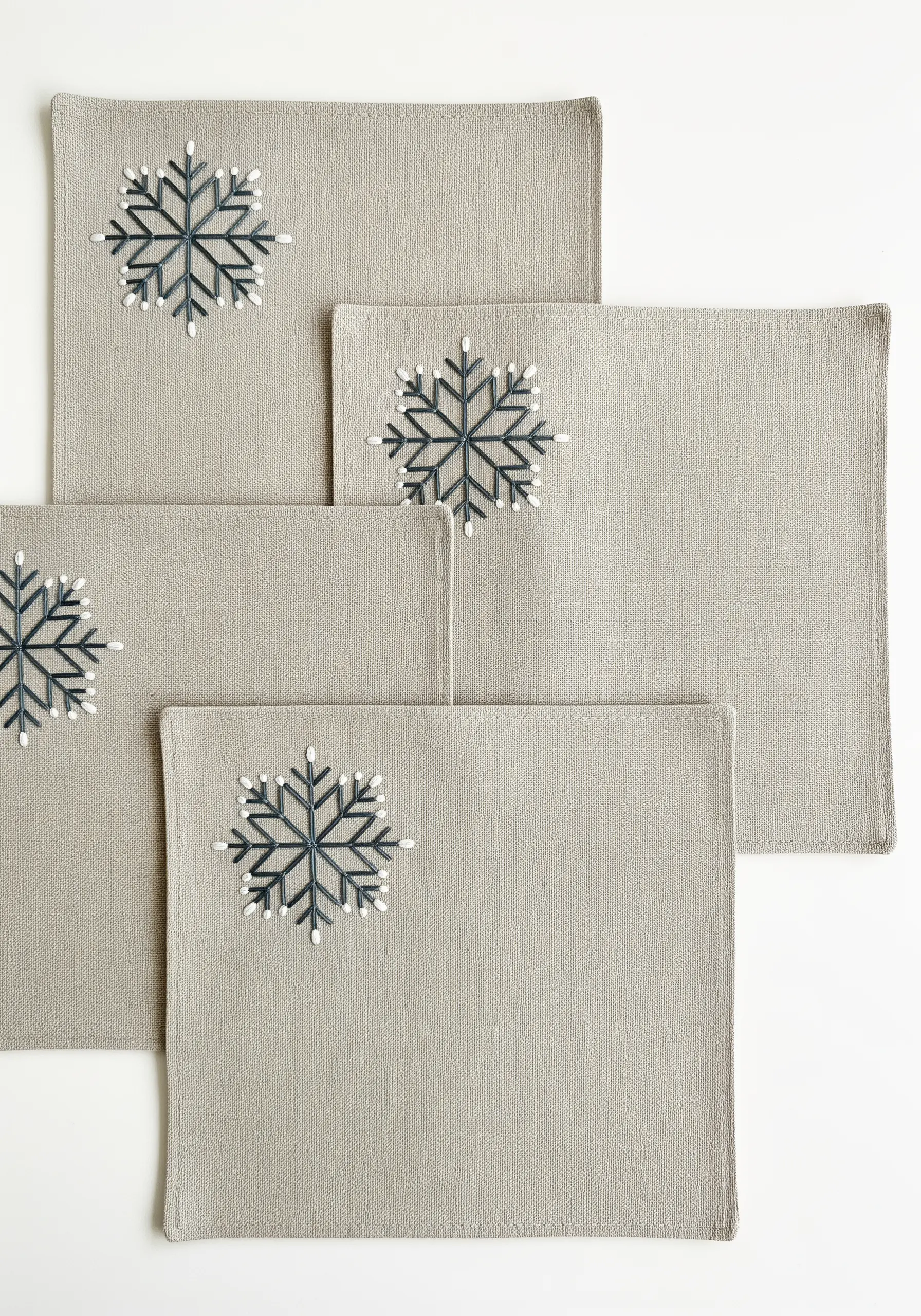 Stylized snowflake embroidered with dark thread and white French knot details.