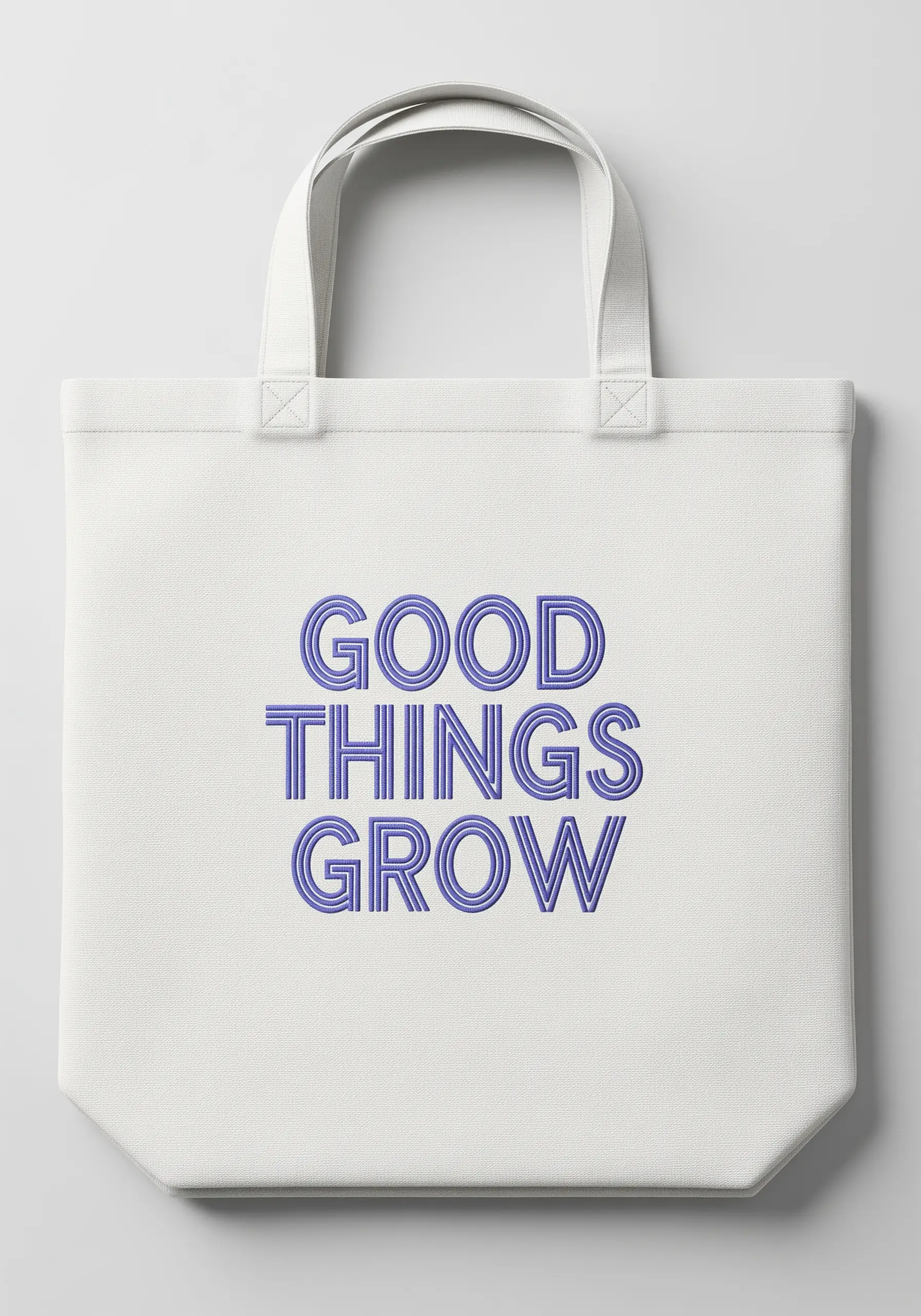 The words 'Good Things Grow' in a triple-line stitch on a white canvas tote.