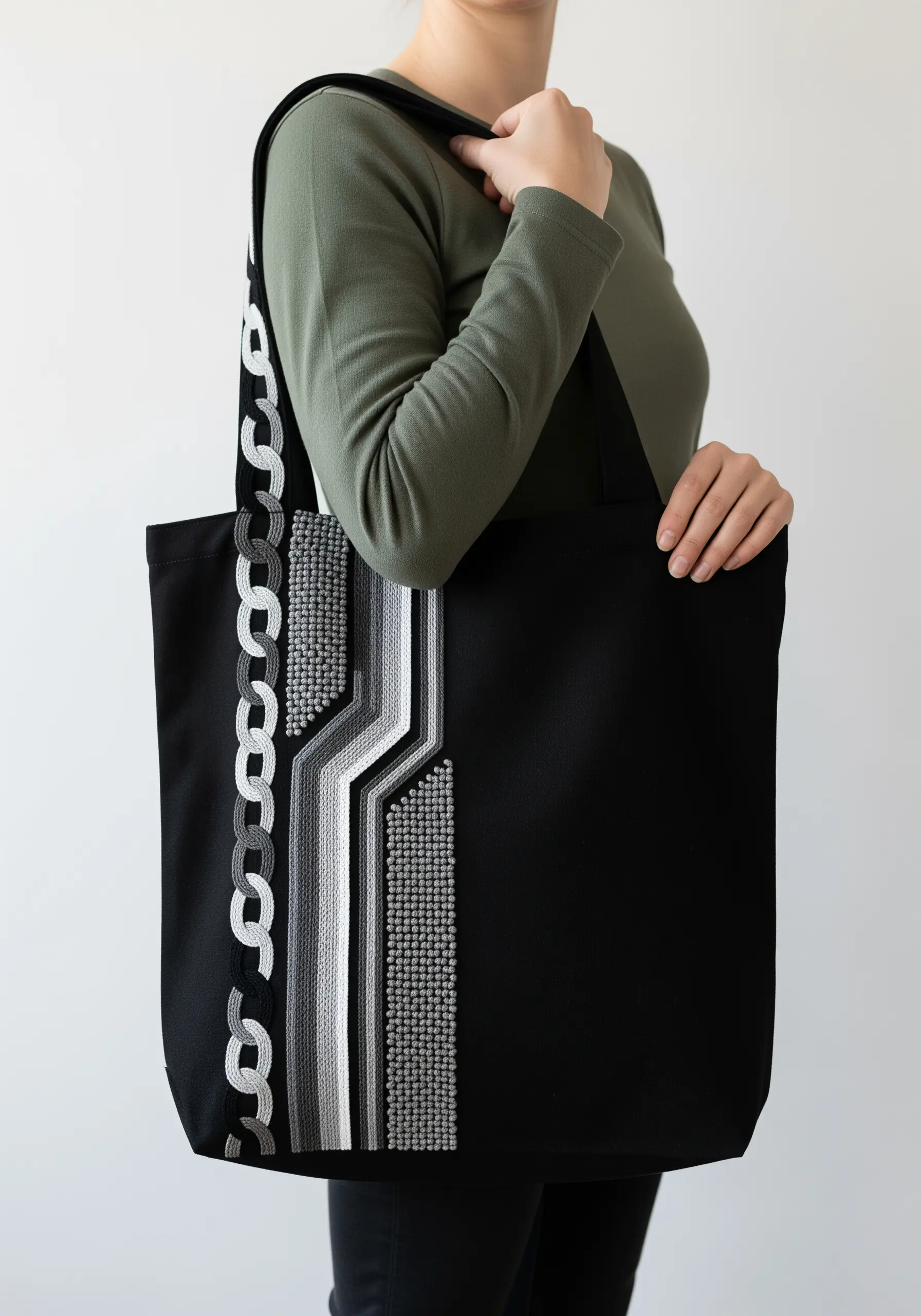 A geometric panel on a black tote bag using grayscale threads and varied textures.