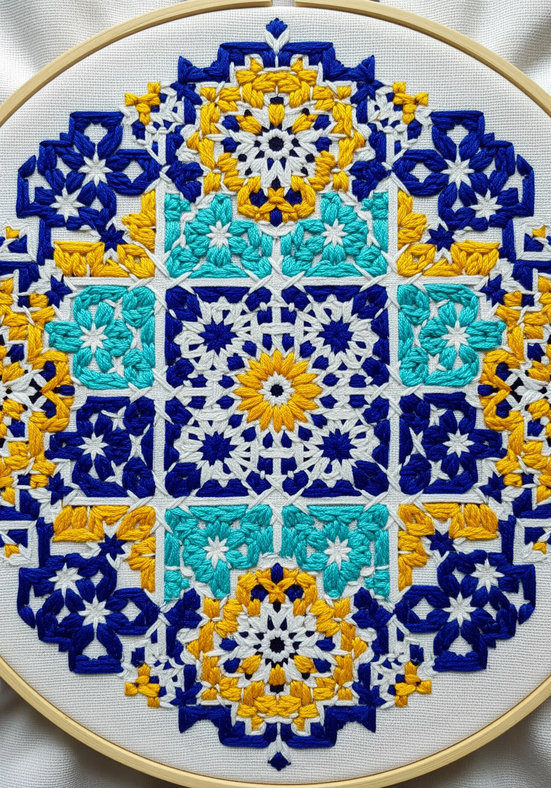 An intricate geometric mandala inspired by Moroccan tiles, stitched in blue, yellow, and turquoise.