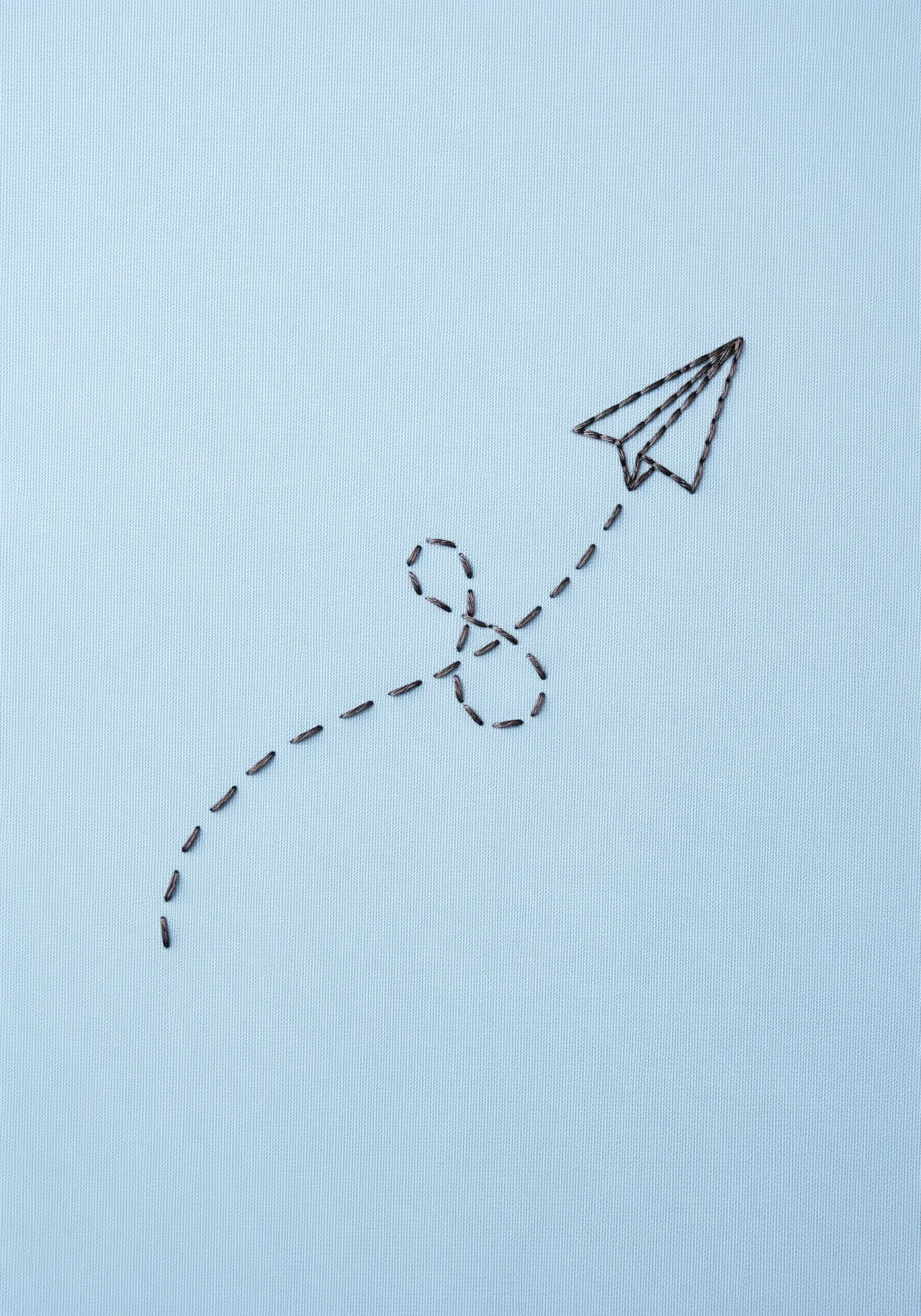 Paper airplane embroidery with a dashed running stitch flight path