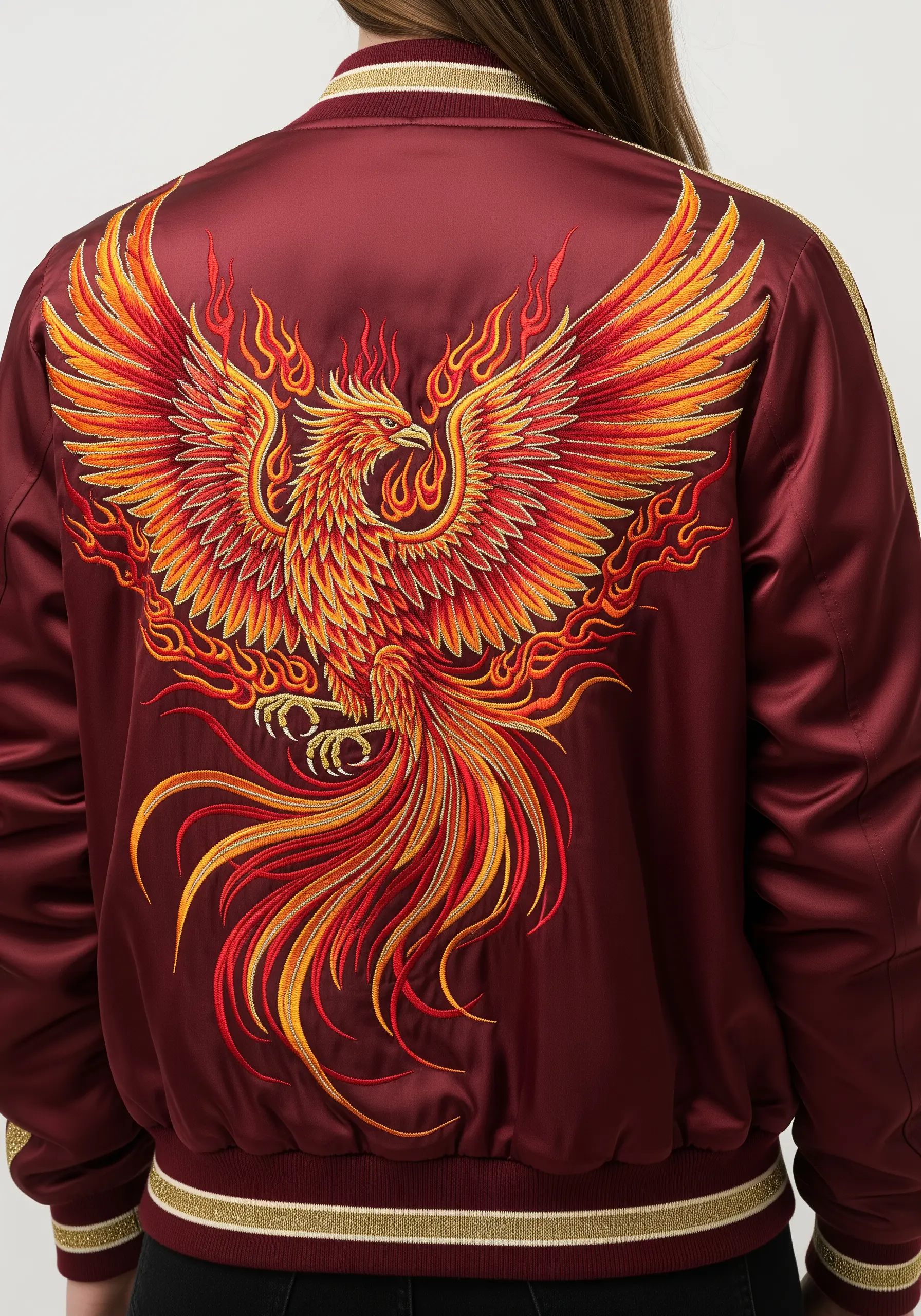 Embroidered phoenix with fiery orange and yellow wings on a burgundy satin bomber jacket.