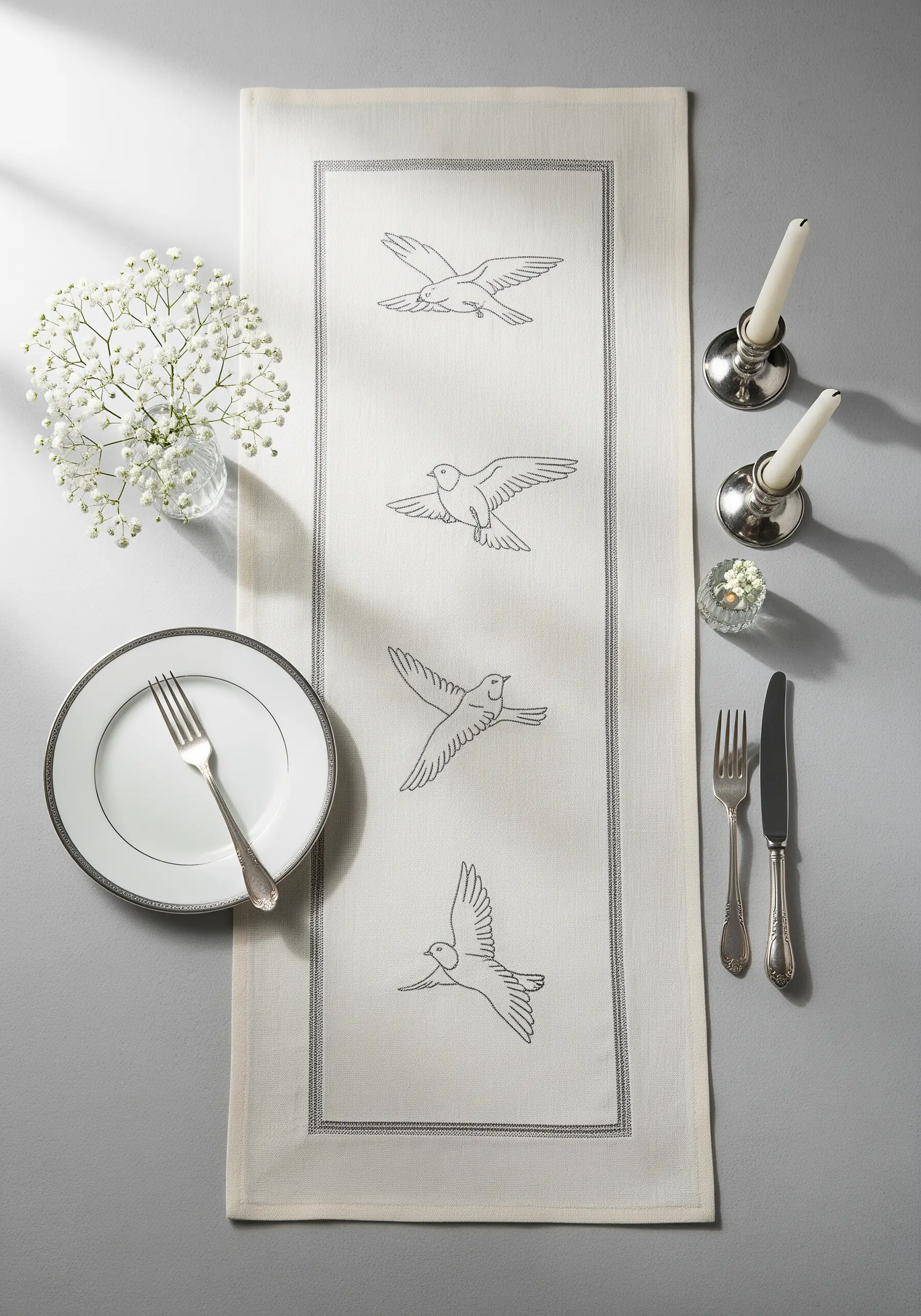 Four birds in flight embroidered in sequence down the center of a formal table runner.