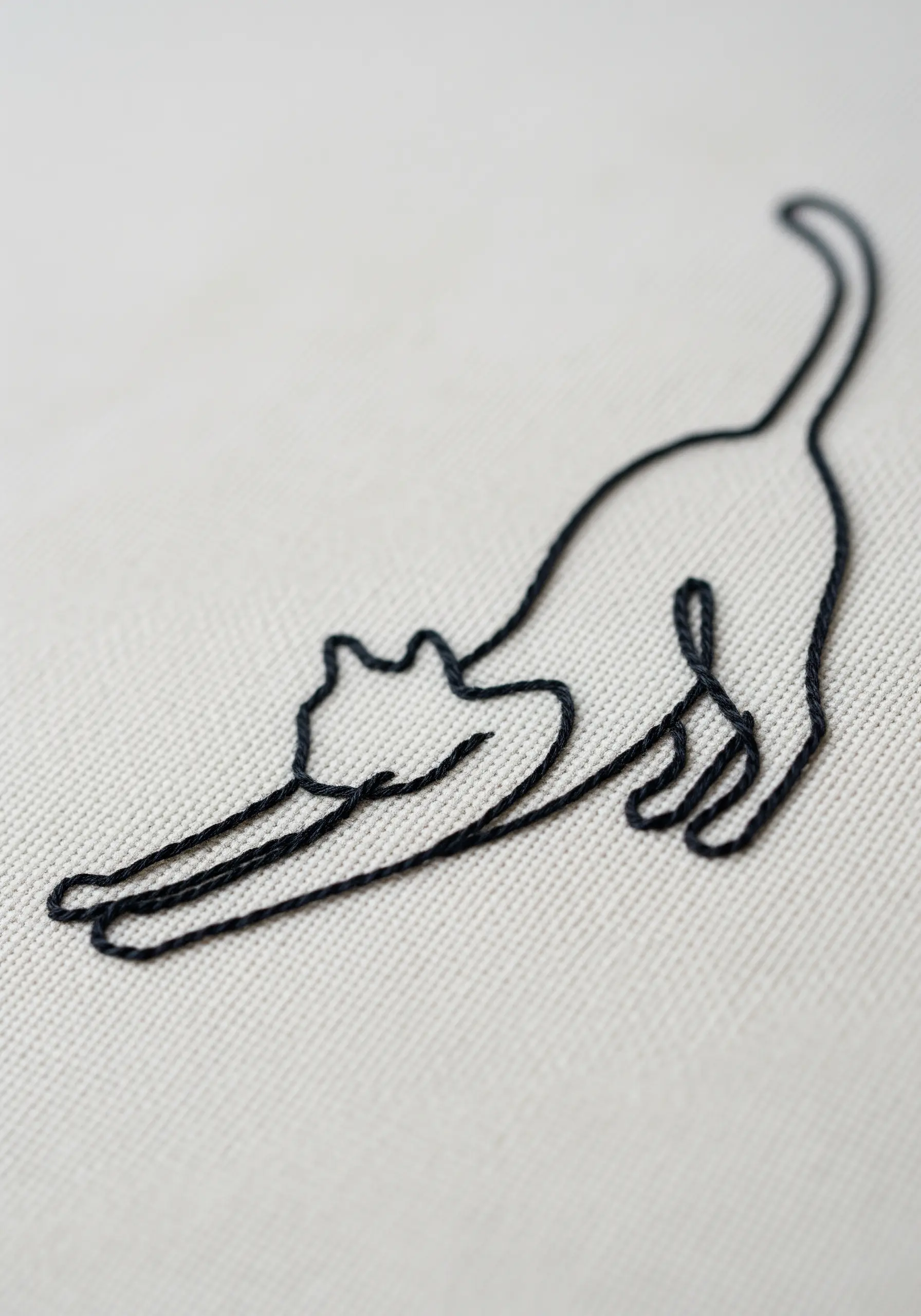 Minimalist black line embroidery of a stretching cat