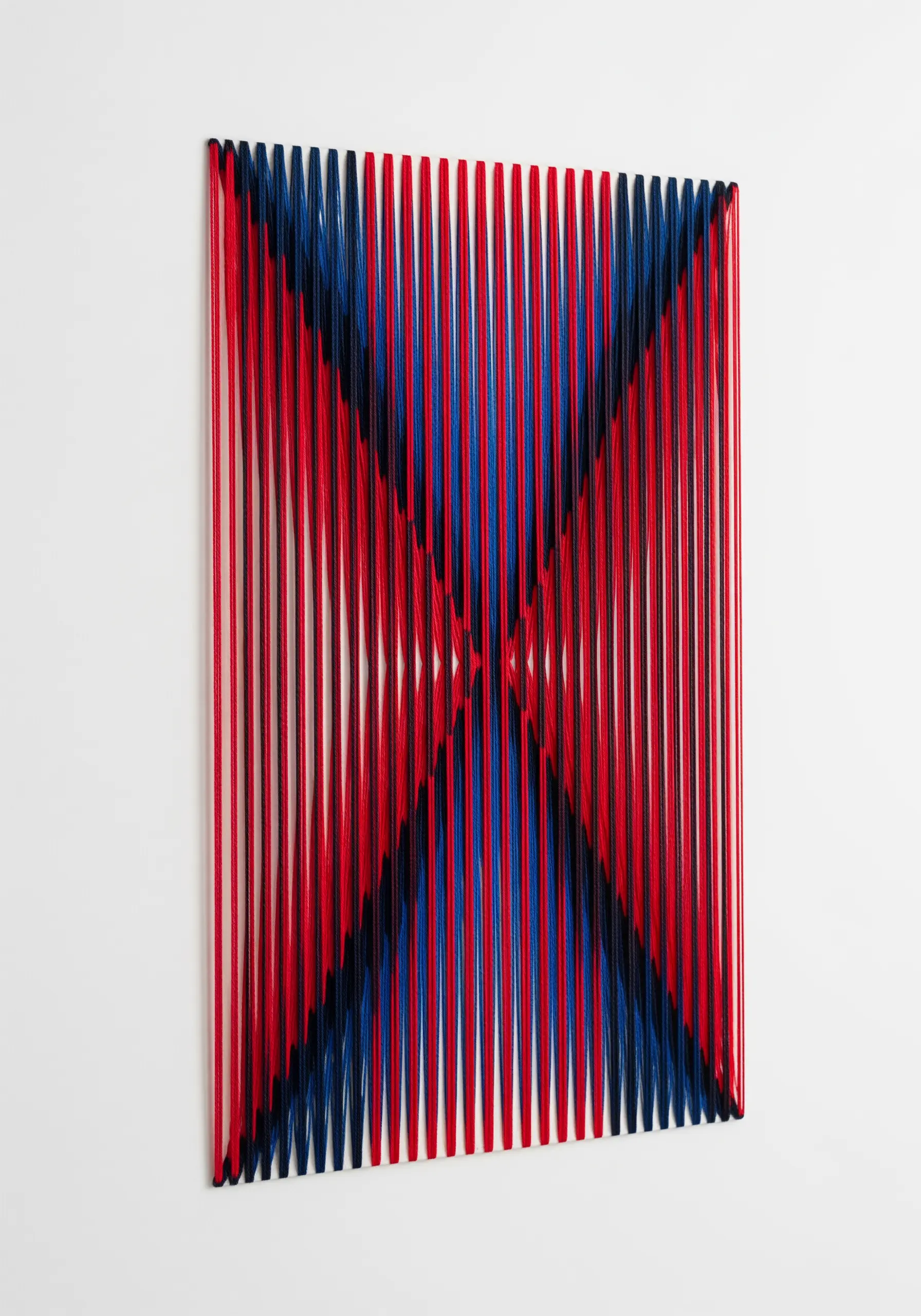 Red, blue, and black thread create a kinetic, three-dimensional op-art pattern.