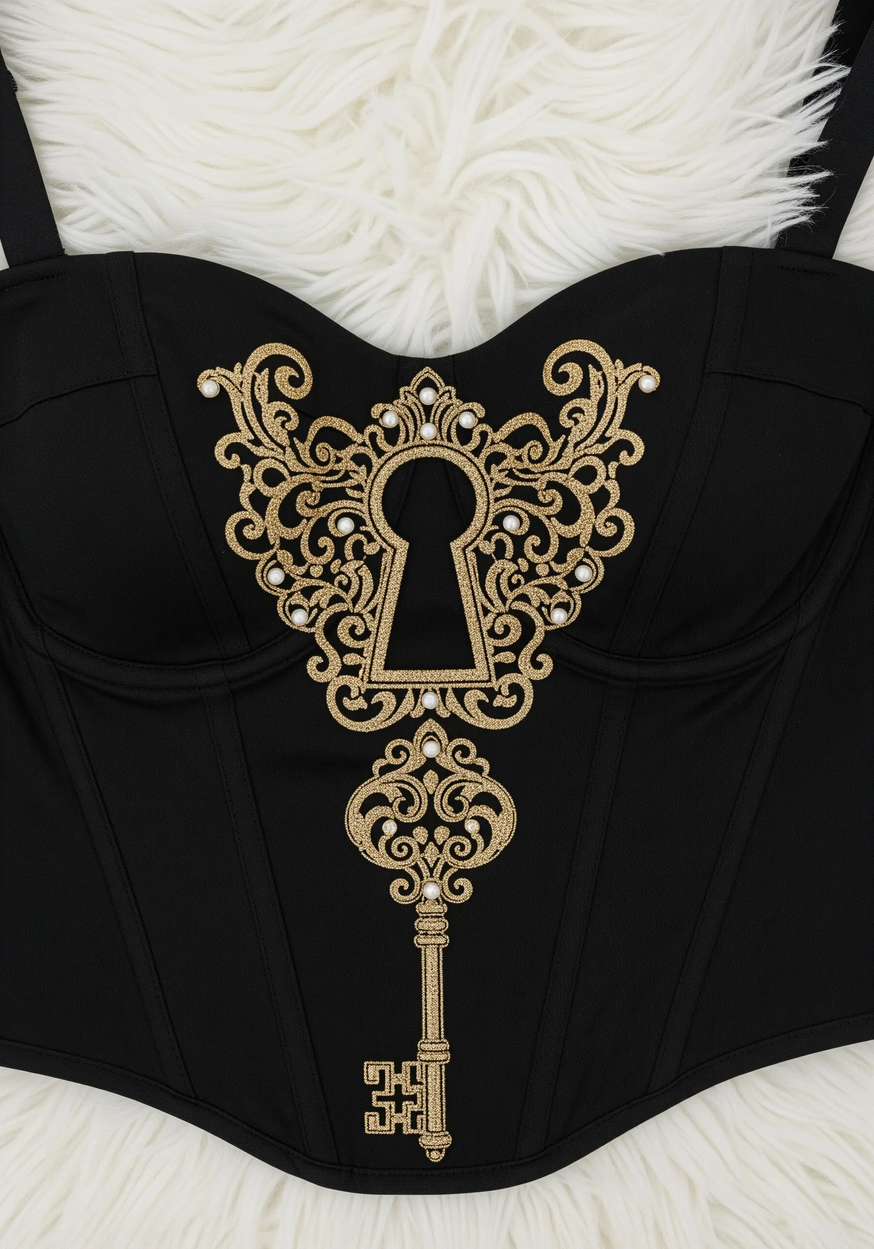 A vintage key and keyhole design in gold glitter thread with pearl accents on a black corset.