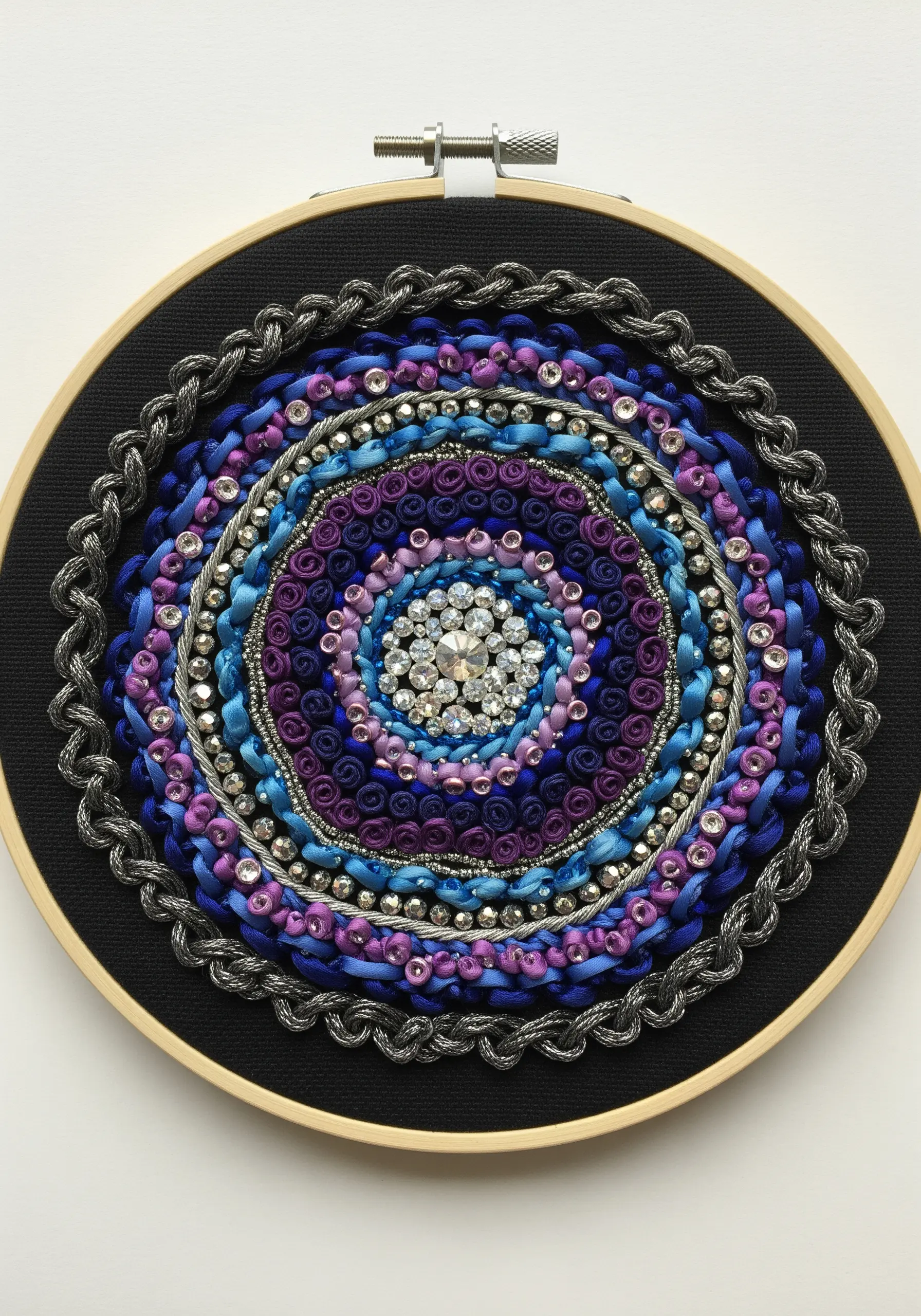 Beaded and ribbon embroidery mandala in purple, blue, and silver on black fabric.