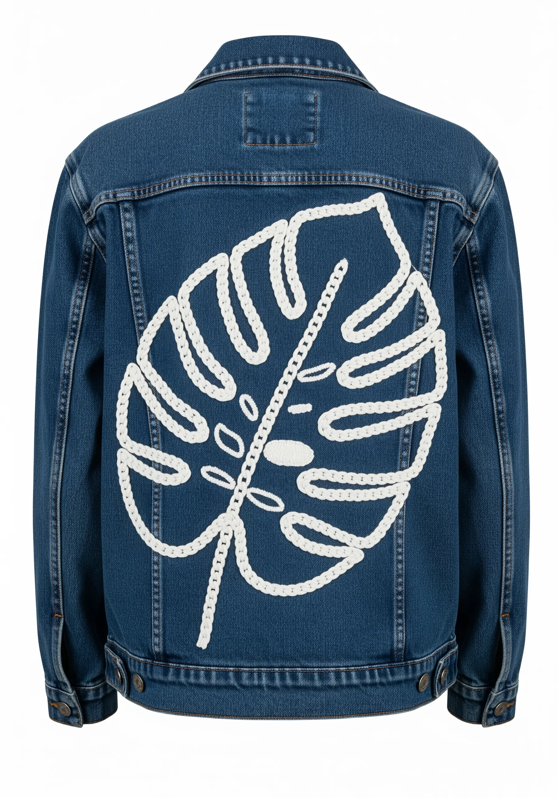 A large monstera leaf outlined in thick white cord on the back of a denim jacket.