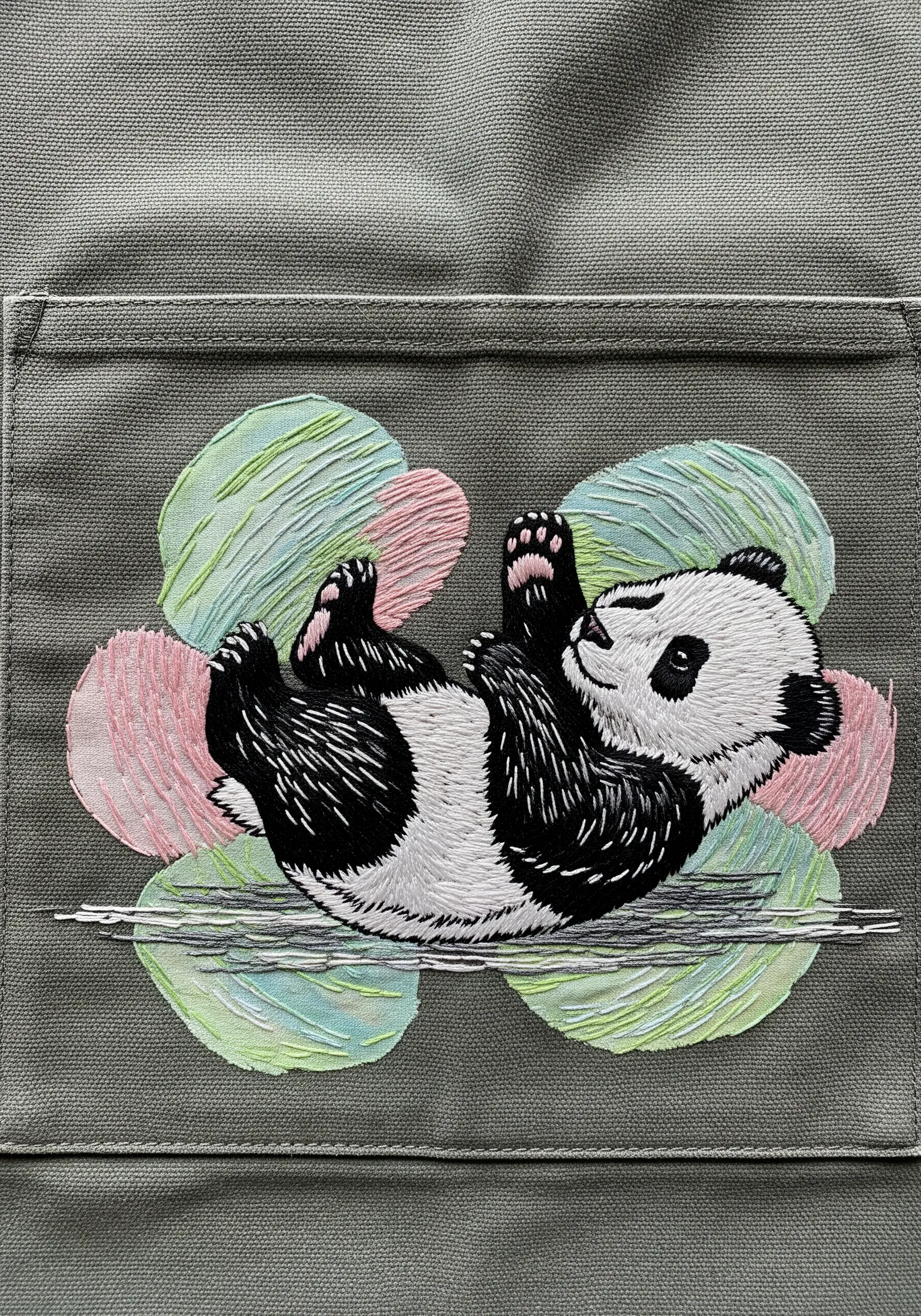 A playful panda embroidered over a background of abstract, painterly stitches in pastel colors.