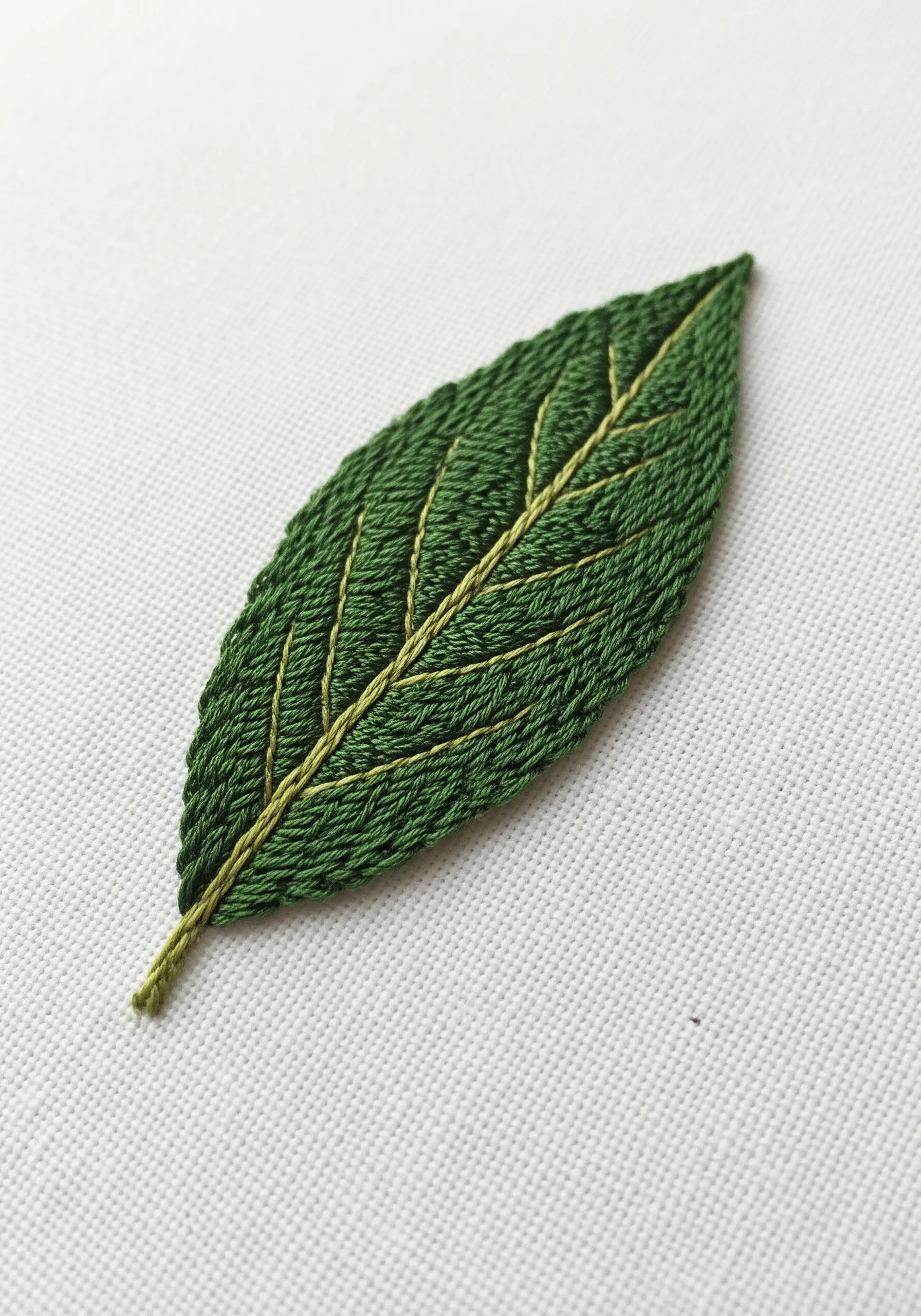 A highly detailed bay leaf embroidered with directional long-and-short stitch and gold veins.