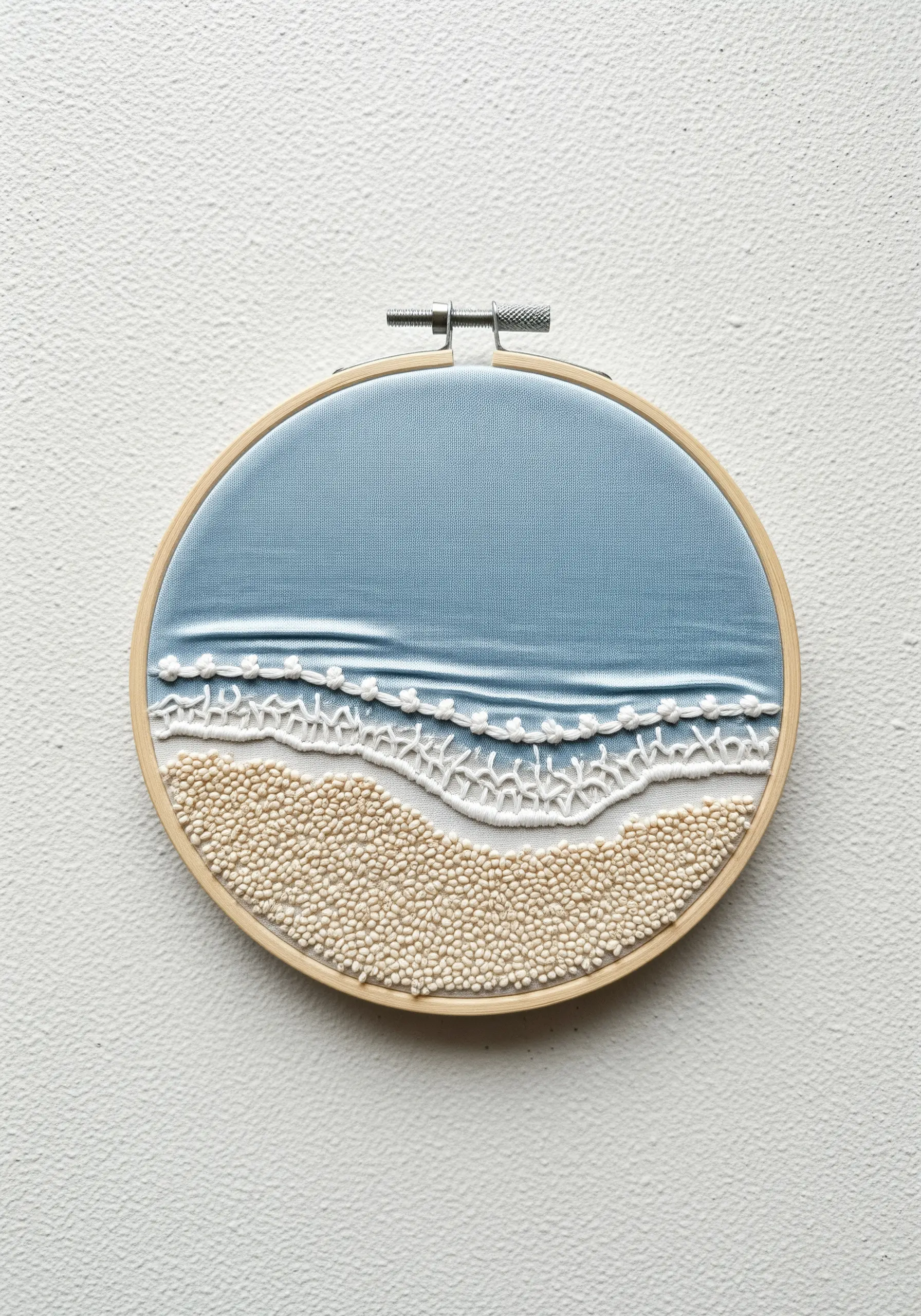 A textured seascape embroidery with fabric for the ocean, lace stitch for foam, and French knots for sand.