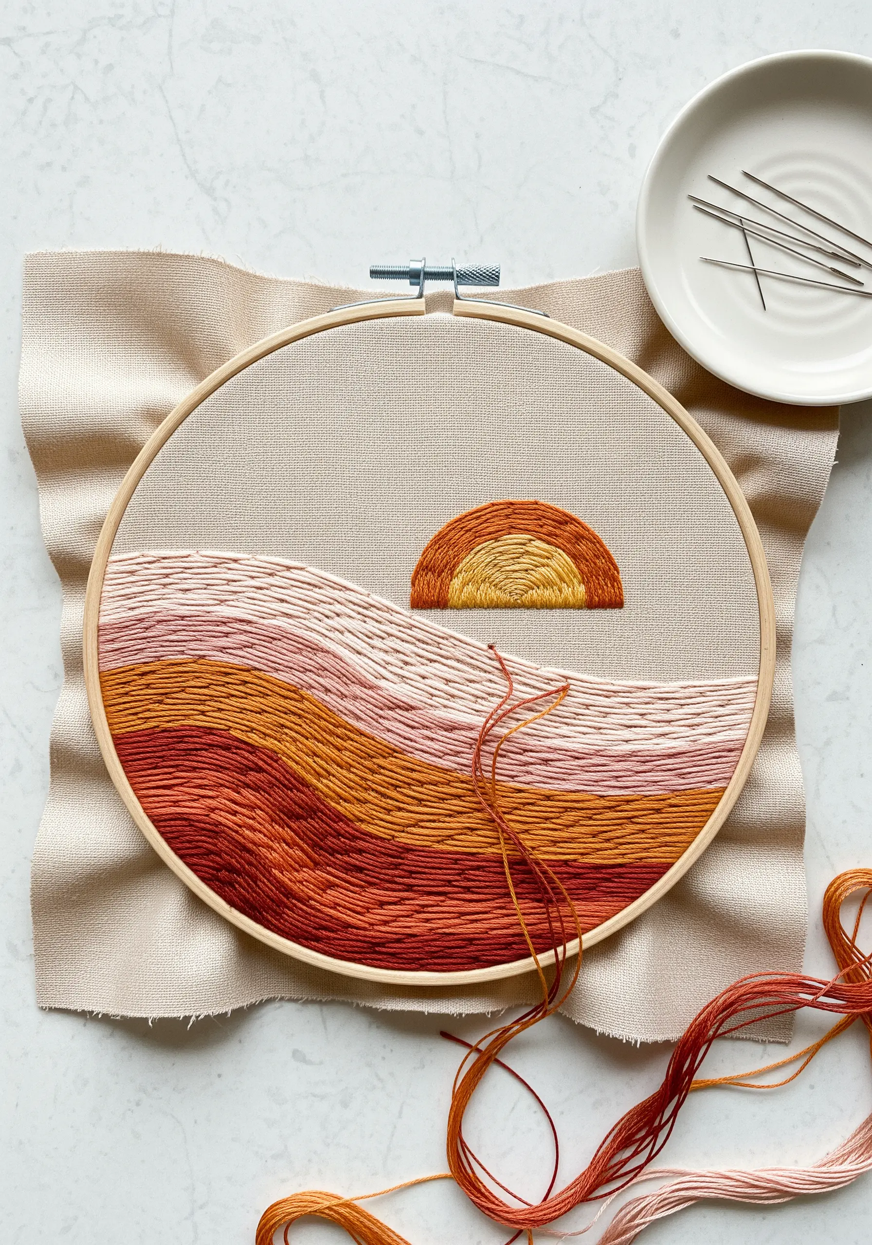 An abstract sunset landscape with textured, horizontal stitches in earthy tones.