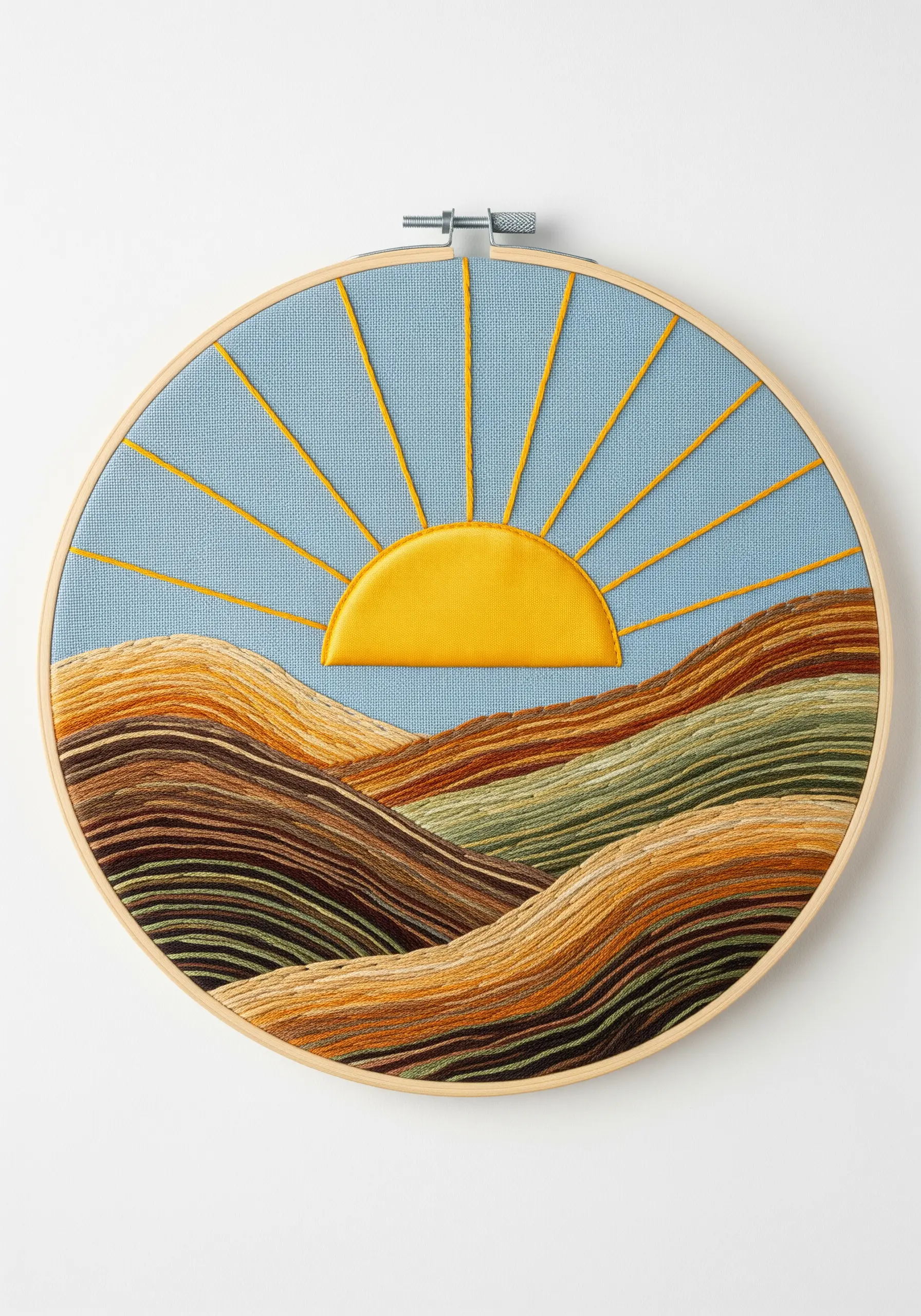 Embroidered landscape with contoured couching stitches in earthy tones and a satin stitch sun.