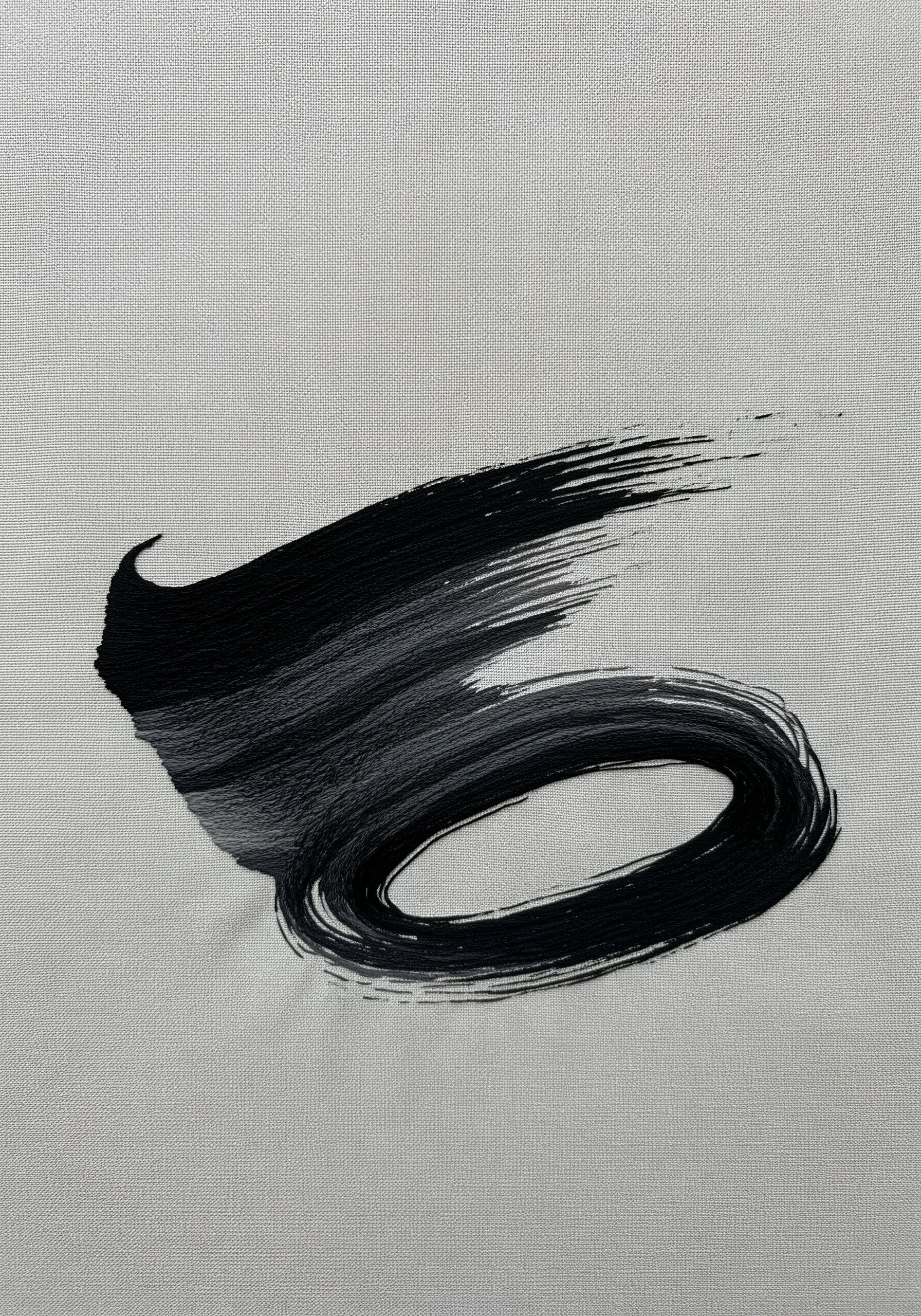 A sweeping, expressive brushstroke embroidered in shades of black and grey thread.