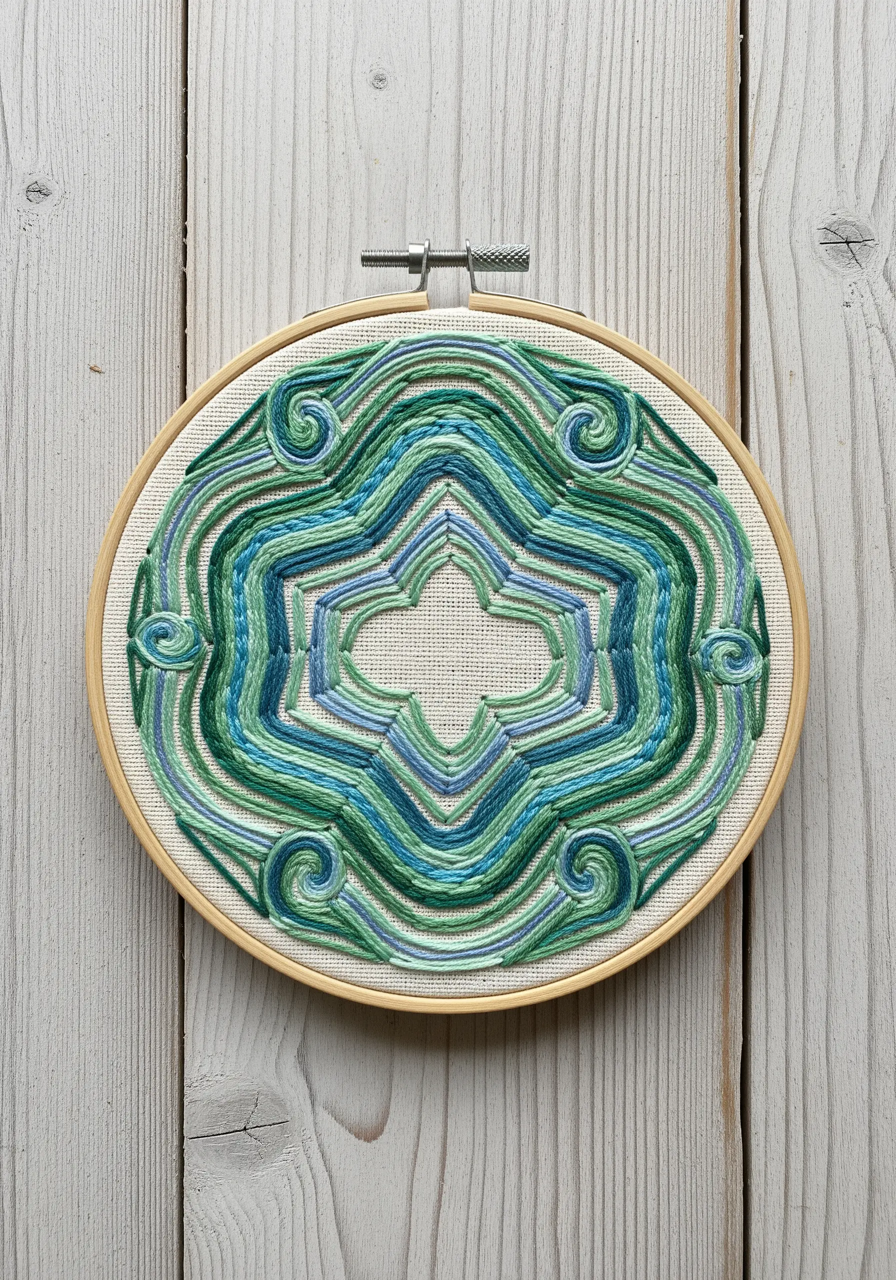 Abstract mandala with wavy lines of variegated blue and green thread.