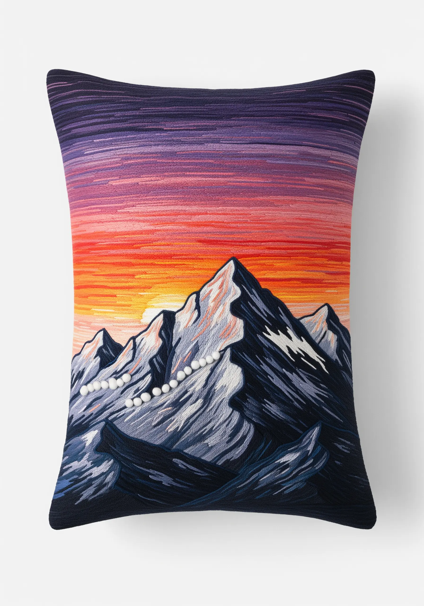 Embroidered mountain landscape on a pillow with a vibrant red, orange, and purple sunset.