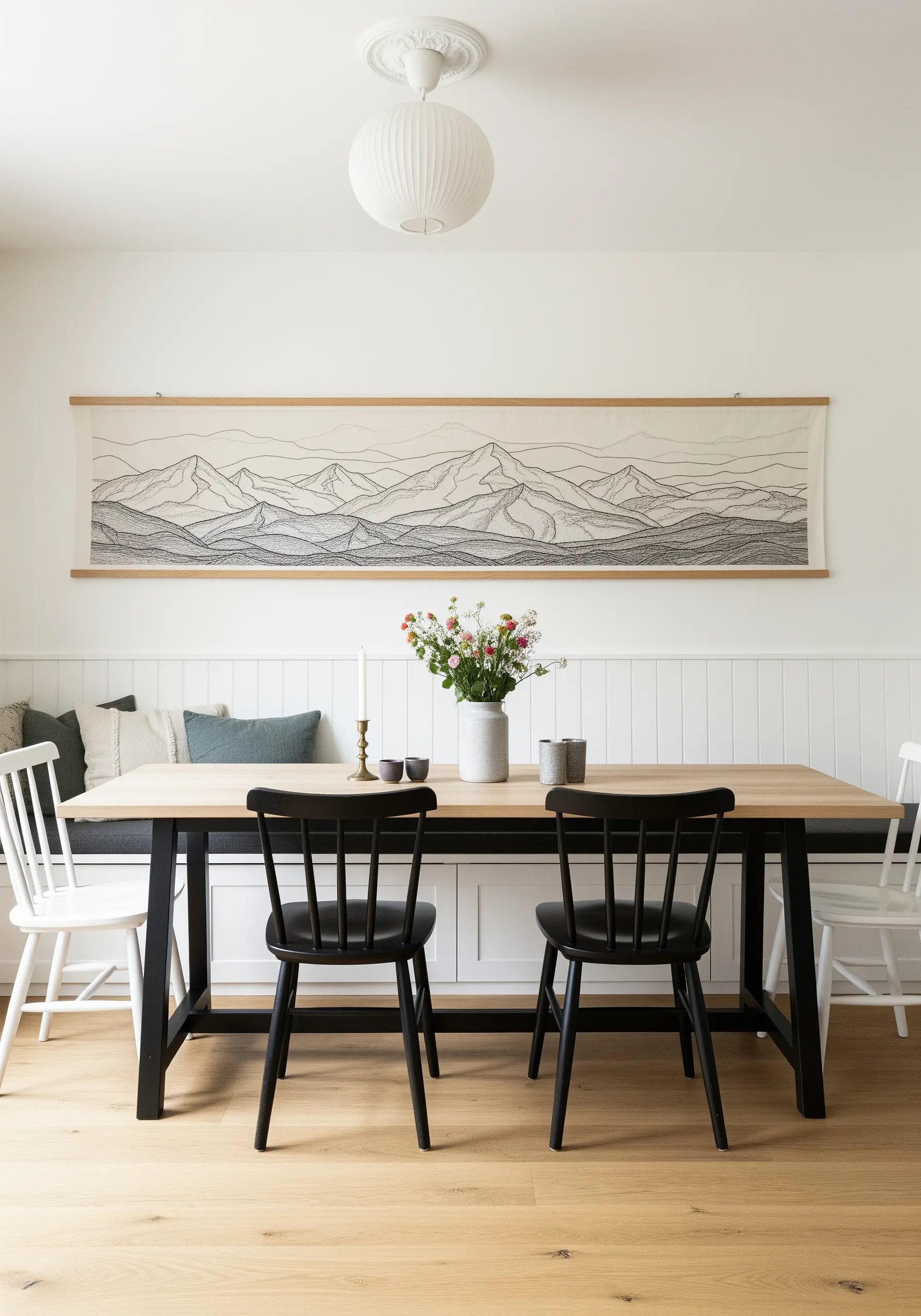 A wide, panoramic embroidered wall hanging of a mountain range in shades of grey.