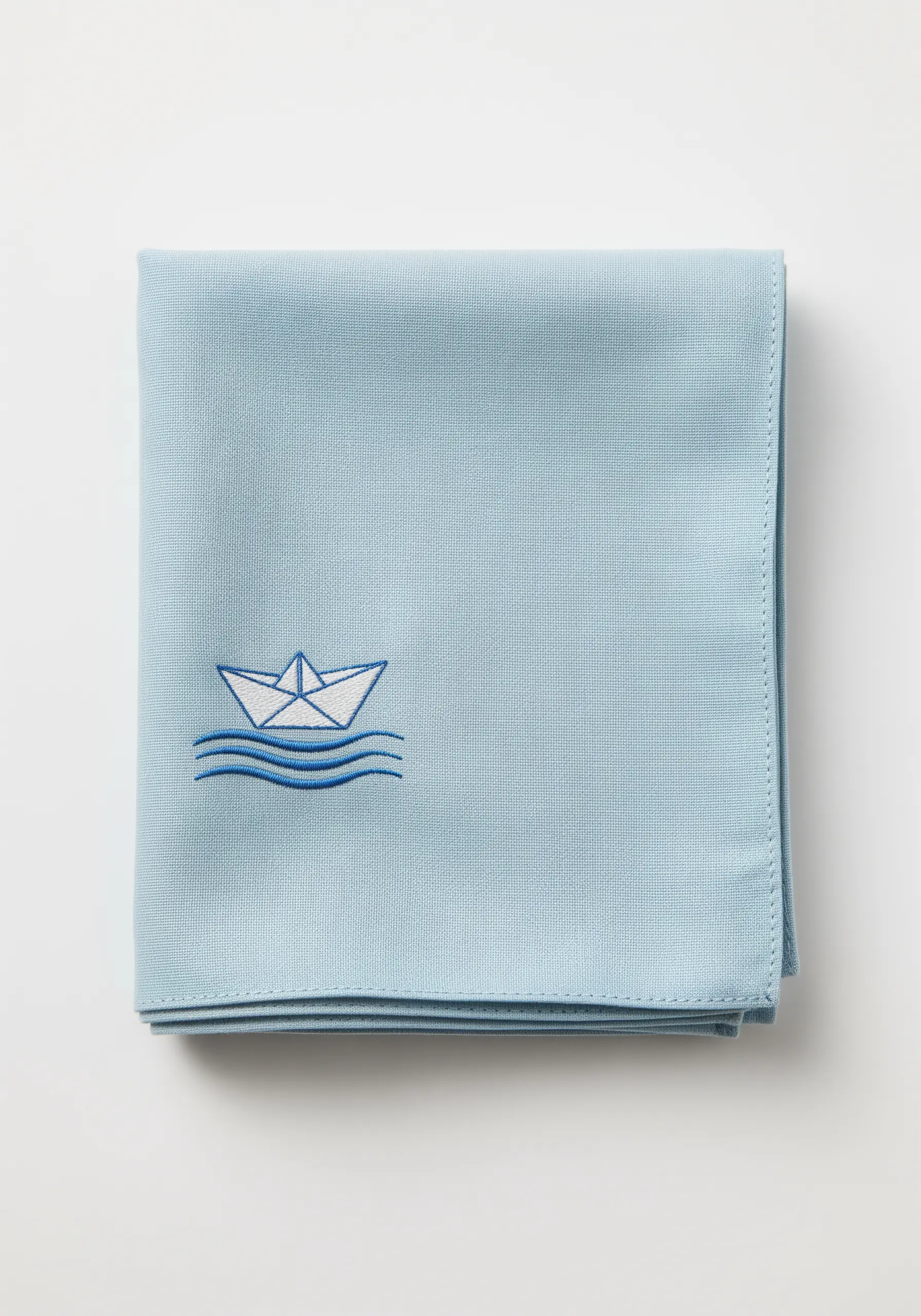 A simple line art paper boat embroidered on a light blue handkerchief.