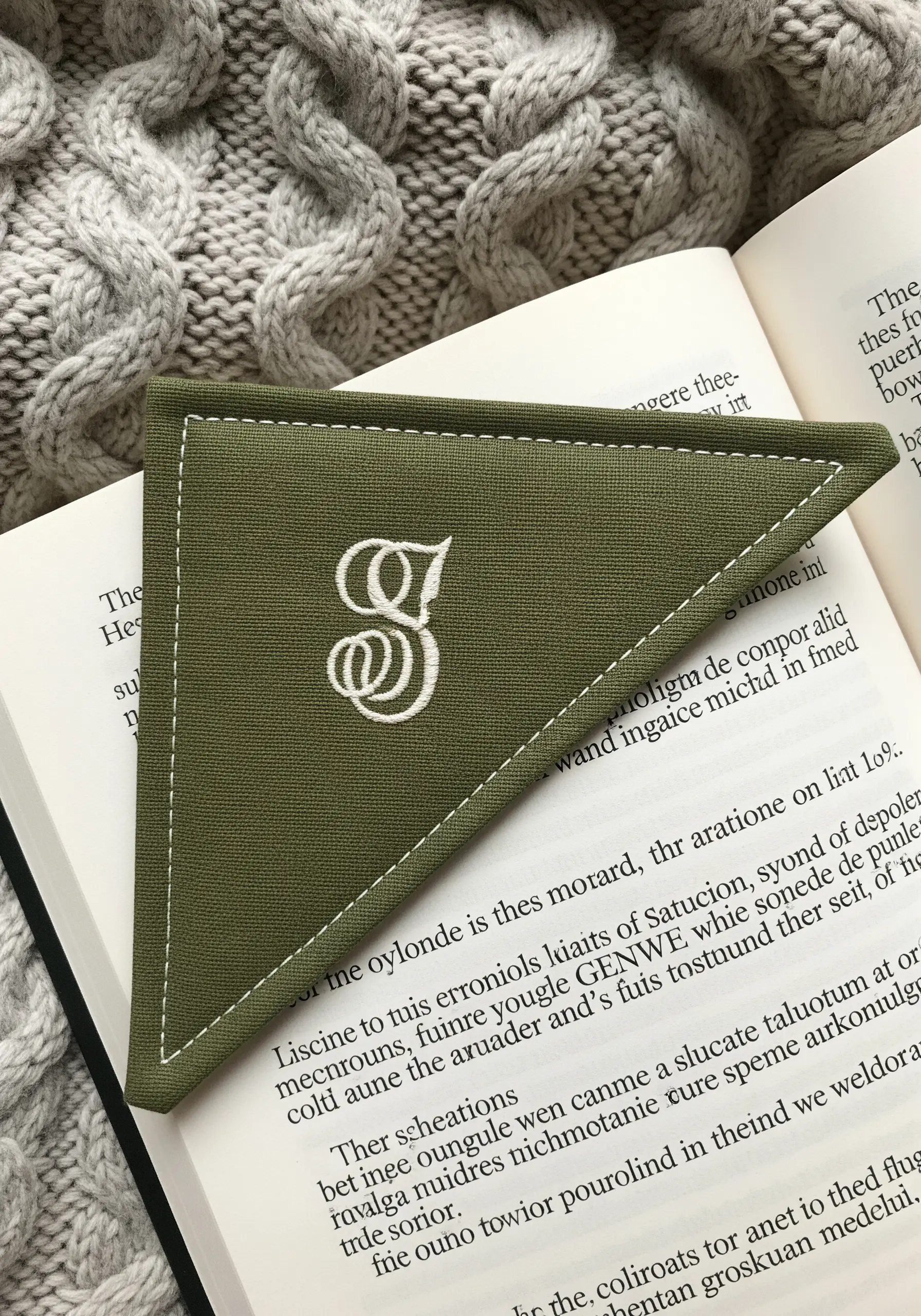 An olive green corner bookmark with a beautifully executed white satin stitch monogram 'G'.