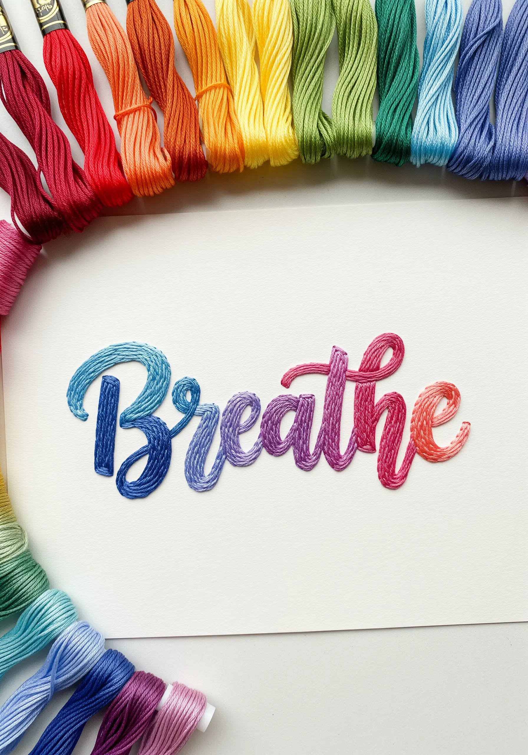 The word 'Breathe' embroidered with a smooth rainbow gradient satin stitch.