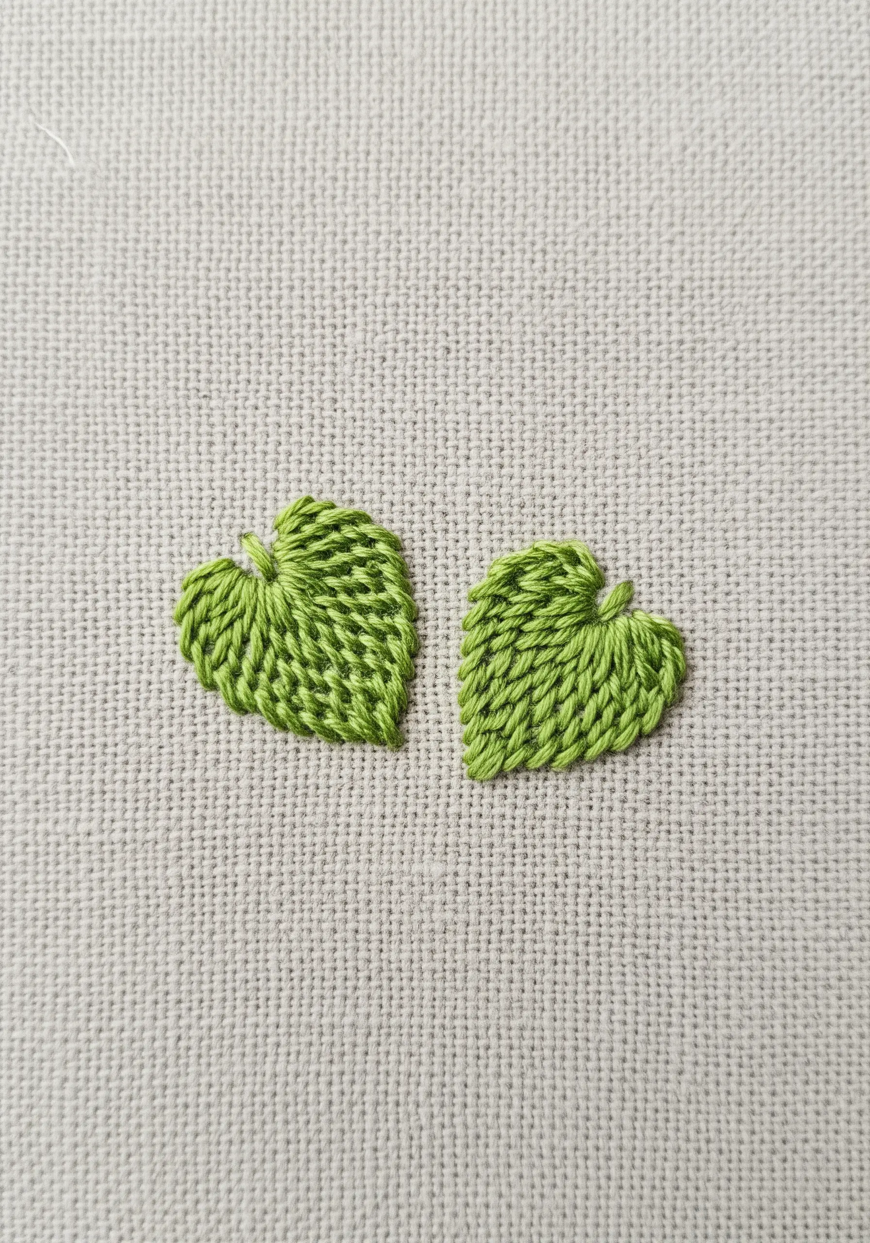 Two tiny, perfectly executed satin-stitched leaves in a bright lime green.