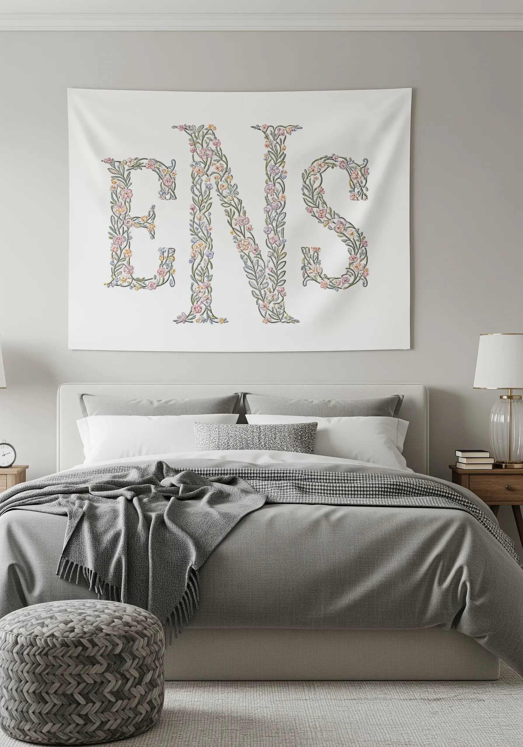 A large fabric wall hanging featuring a three-letter monogram filled with intricate floral embroidery.
